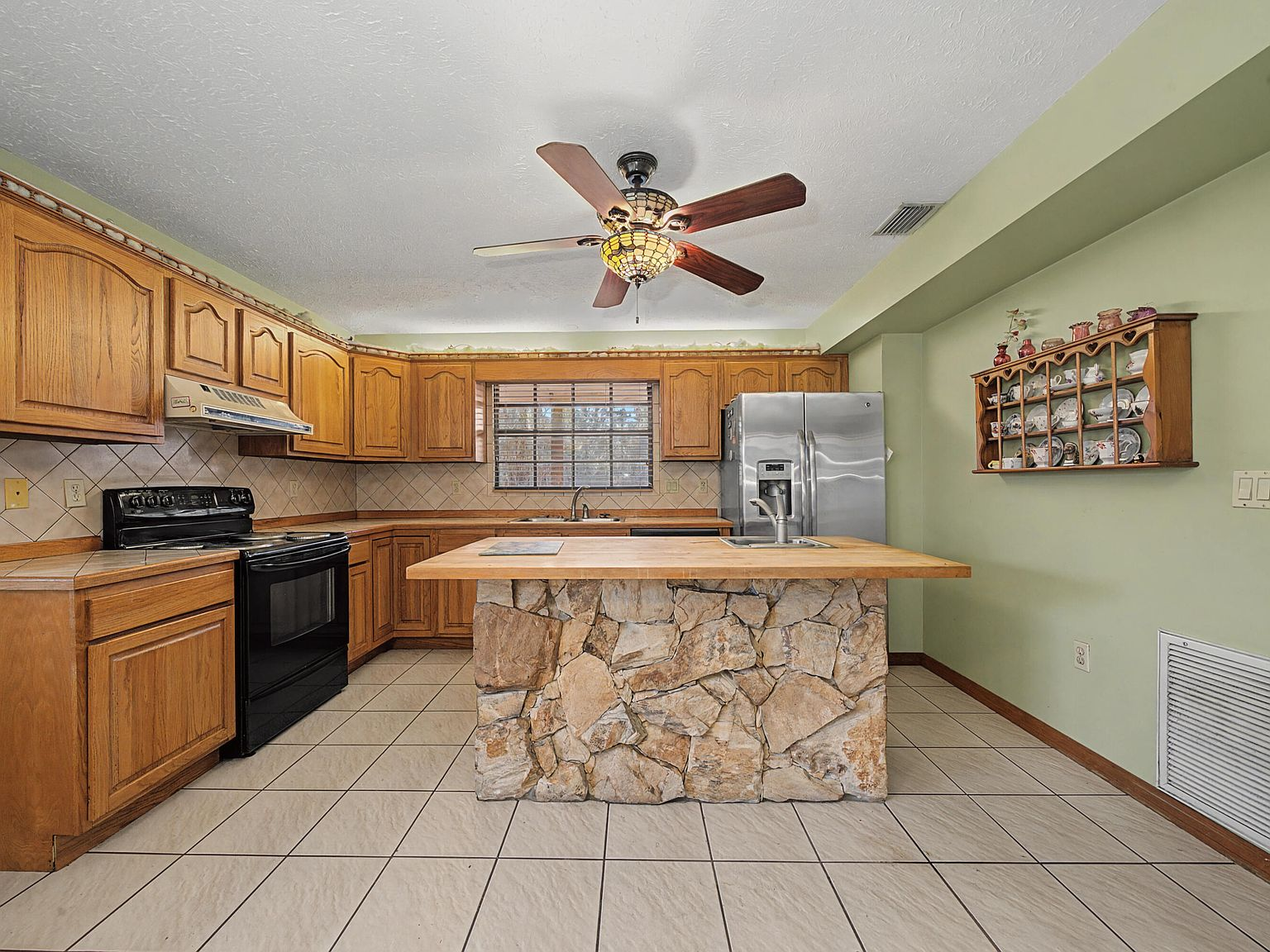 Kitchen wide-angle showing flagstone-clad island and raised-panel cabinetry