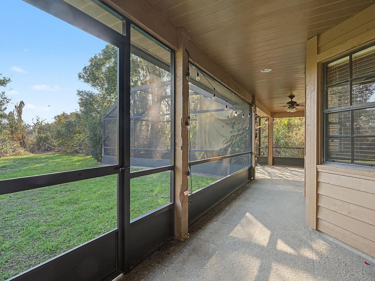 Spacious covered screened-in porch with wood-paneled ceiling