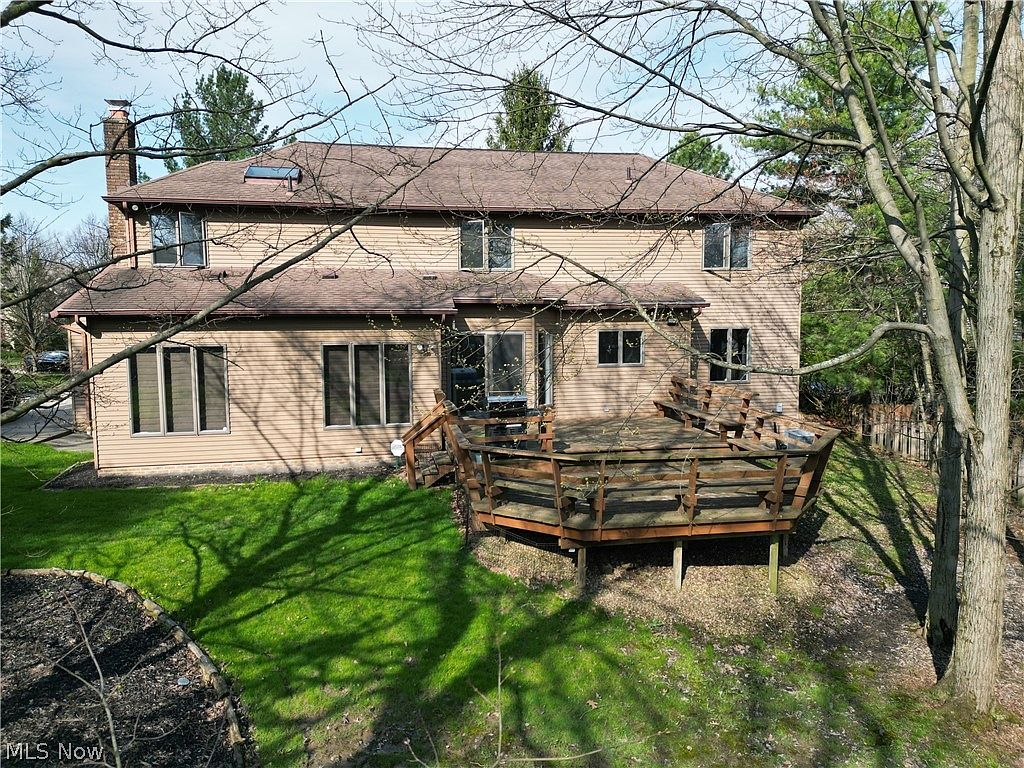 Rear of the home with large wrap-around wooden deck and open lawn