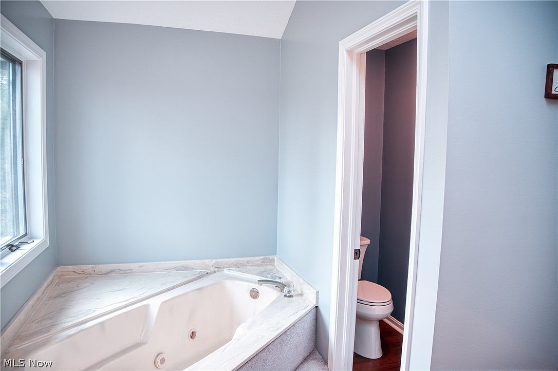 Primary bathroom with jetted soaking tub and marble-look surround