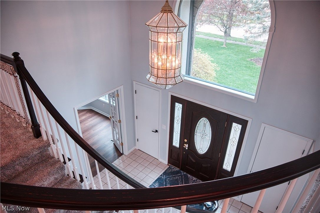 Two-story foyer with Palladian window, dark wood handrail, and hanging chandelier