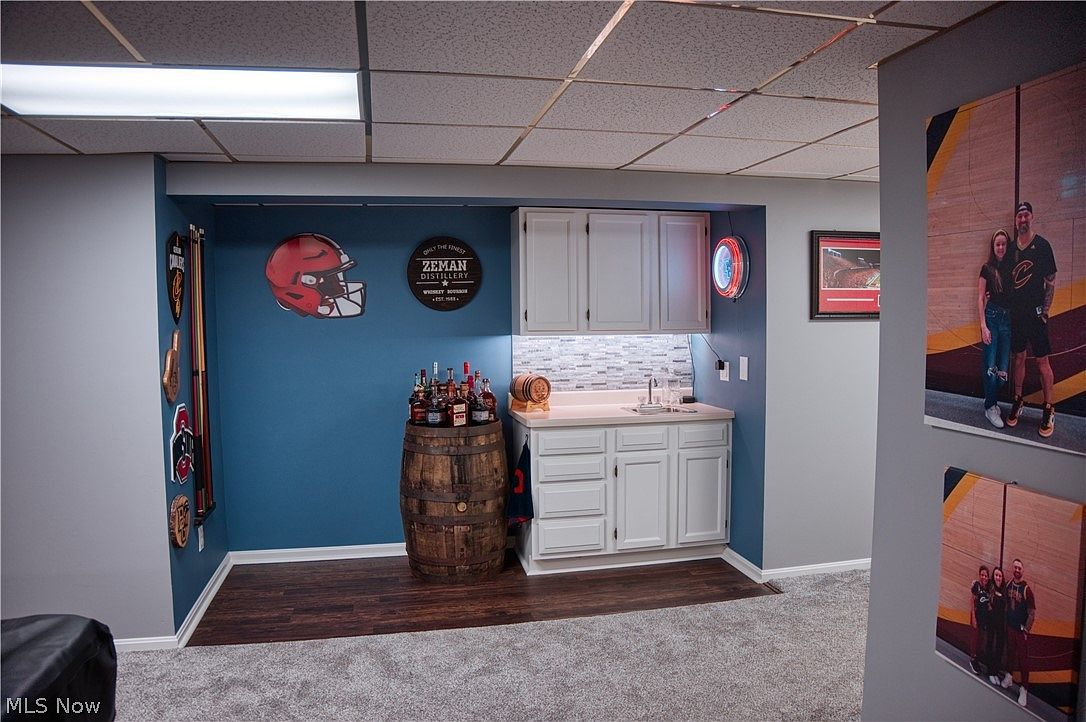 Finished basement wet bar area with vinyl plank flooring and blue accent wall