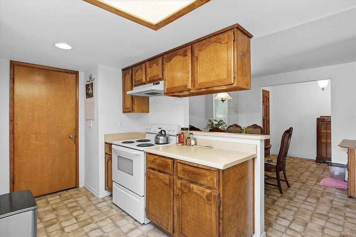 Kitchen showing transition to dining area with honey-oak cabinetry and white appliances