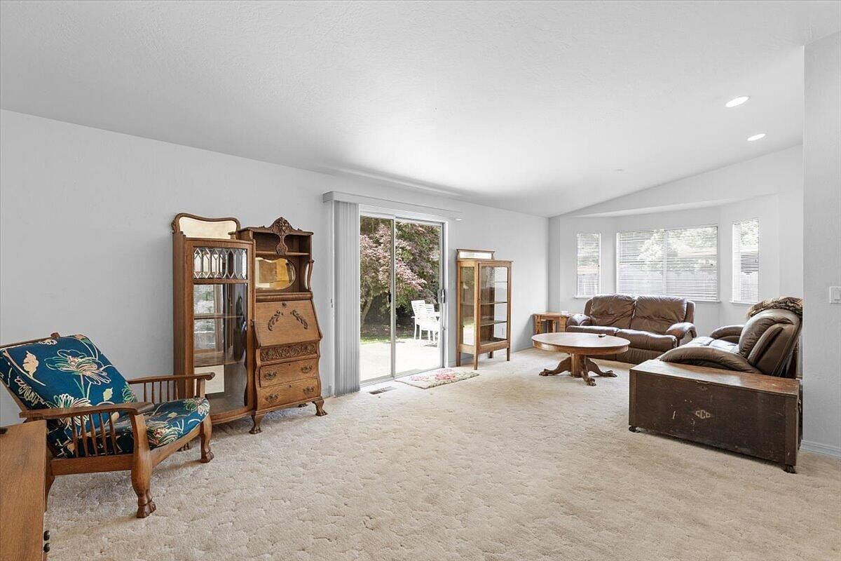 Living room wide-angle view showing vaulted ceiling, sliding glass door, and open layout