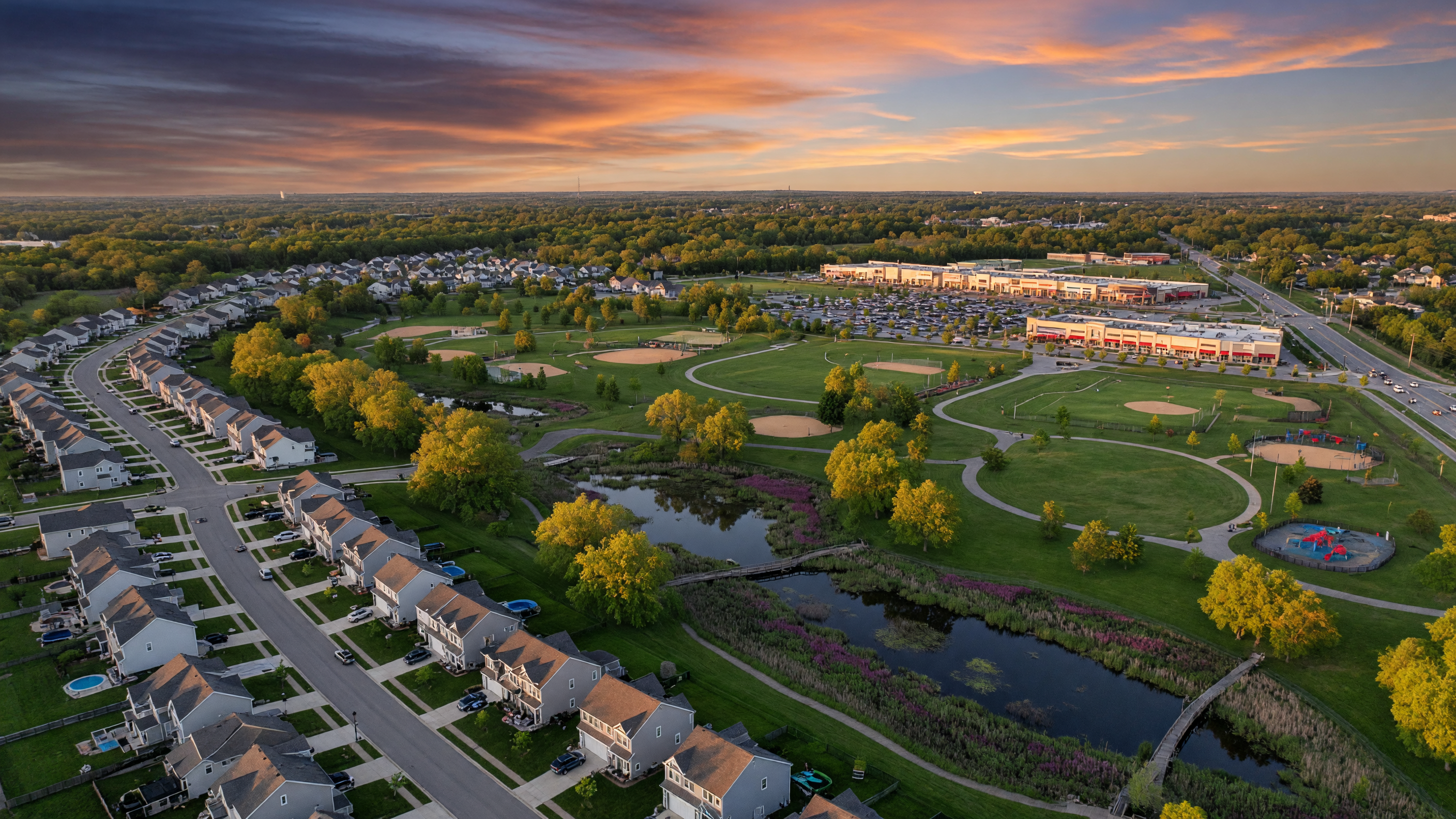 Aerial view of Beavercreek Ohio suburban landscape with green spaces, modern neighborhoods, and wetlands at sunset