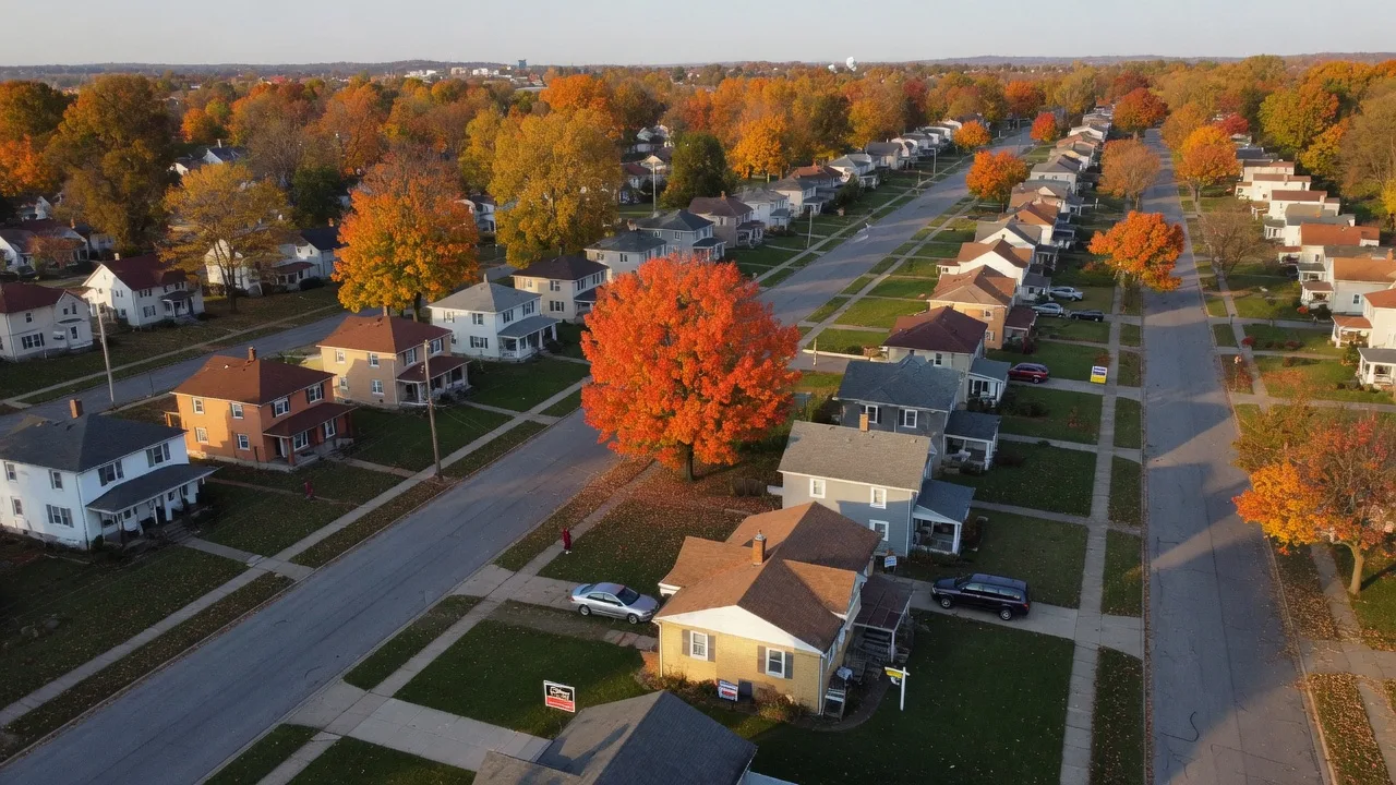 Aerial view of a residential neighborhood in the greater Dayton Ohio area with tree-lined streets and for-sale signs on well-maintained homes
