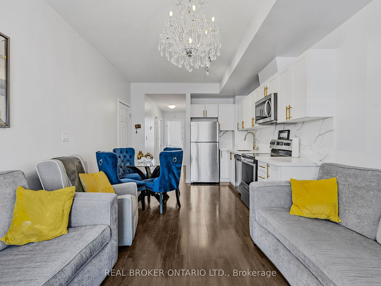 Kitchen viewed from the open-concept living area with staged furnishings visible in background — virtually staged