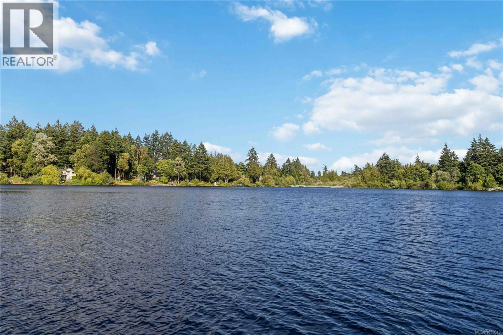 Scenic view of Glen Lake with calm blue water, dense evergreen forest, and scattered clouds