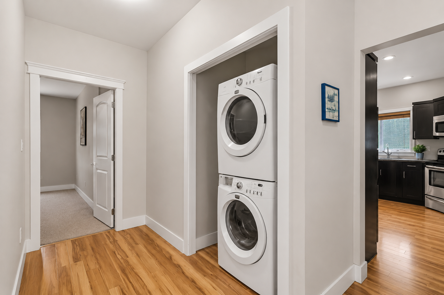 Hallway laundry area with stacked washer and dryer in a clean, modern alcove