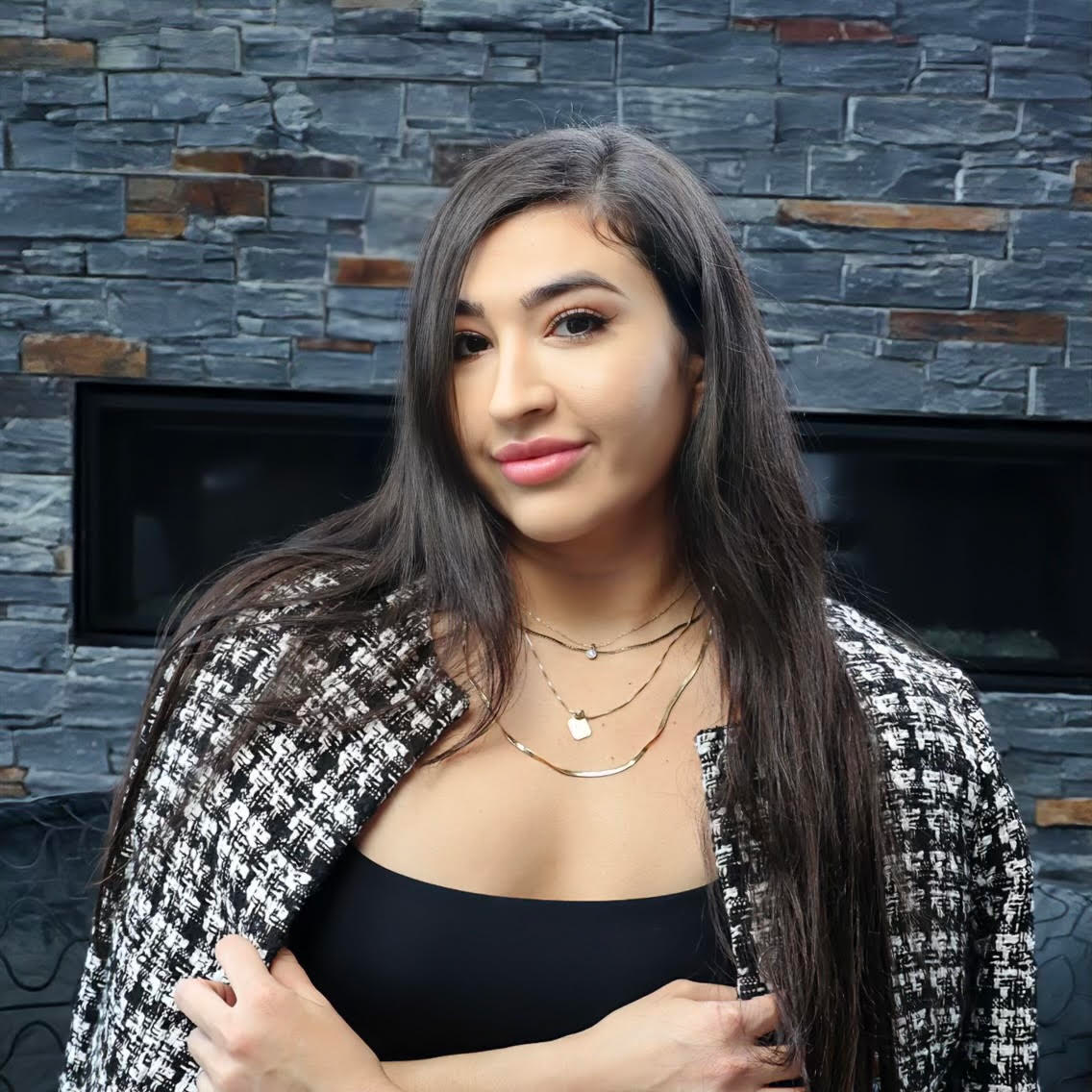 Paulina Gomez, professional headshot in a tweed jacket against a stone fireplace backdrop