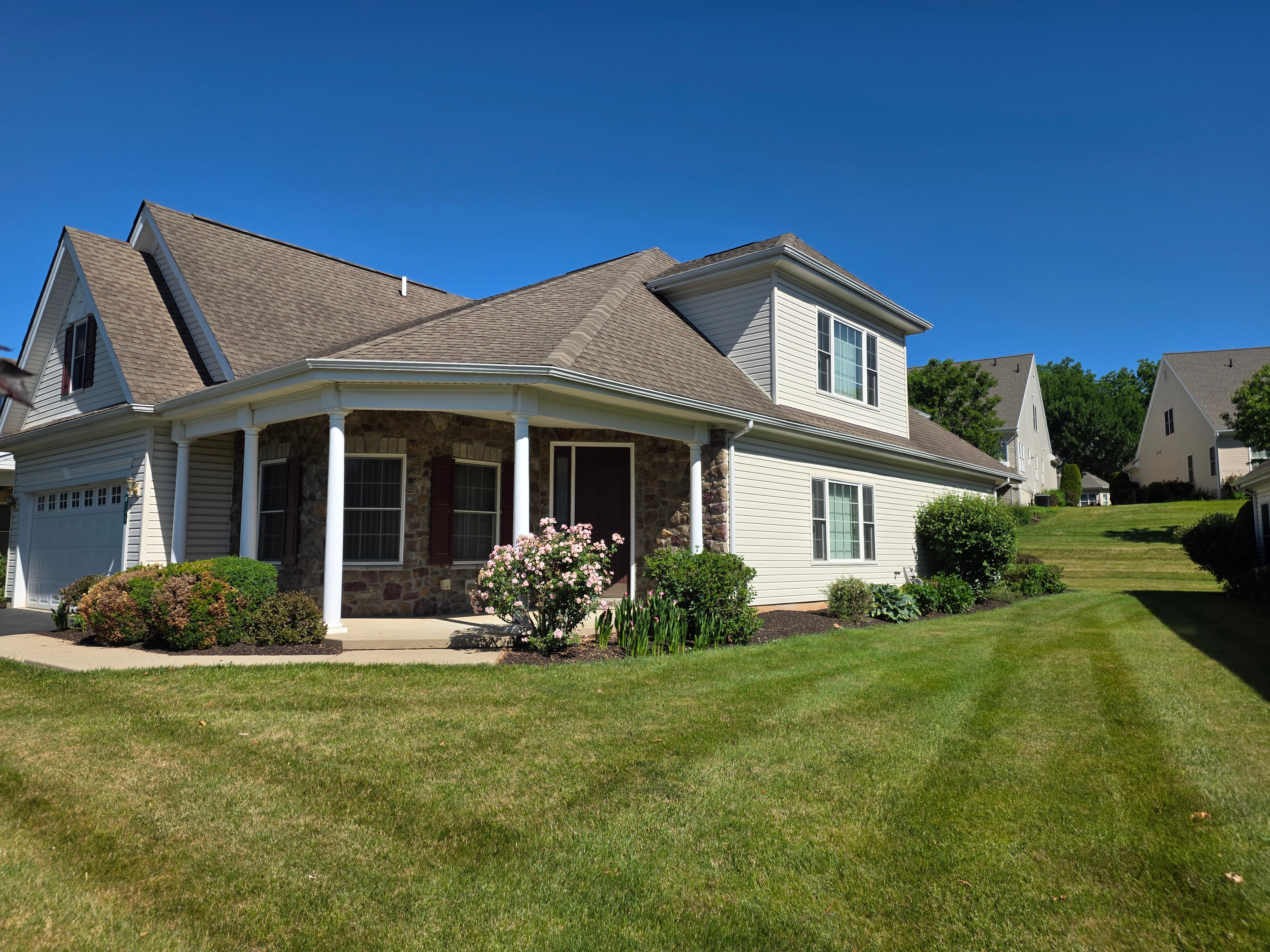 Front facade with stone accents, white porch columns, and gabled roofline