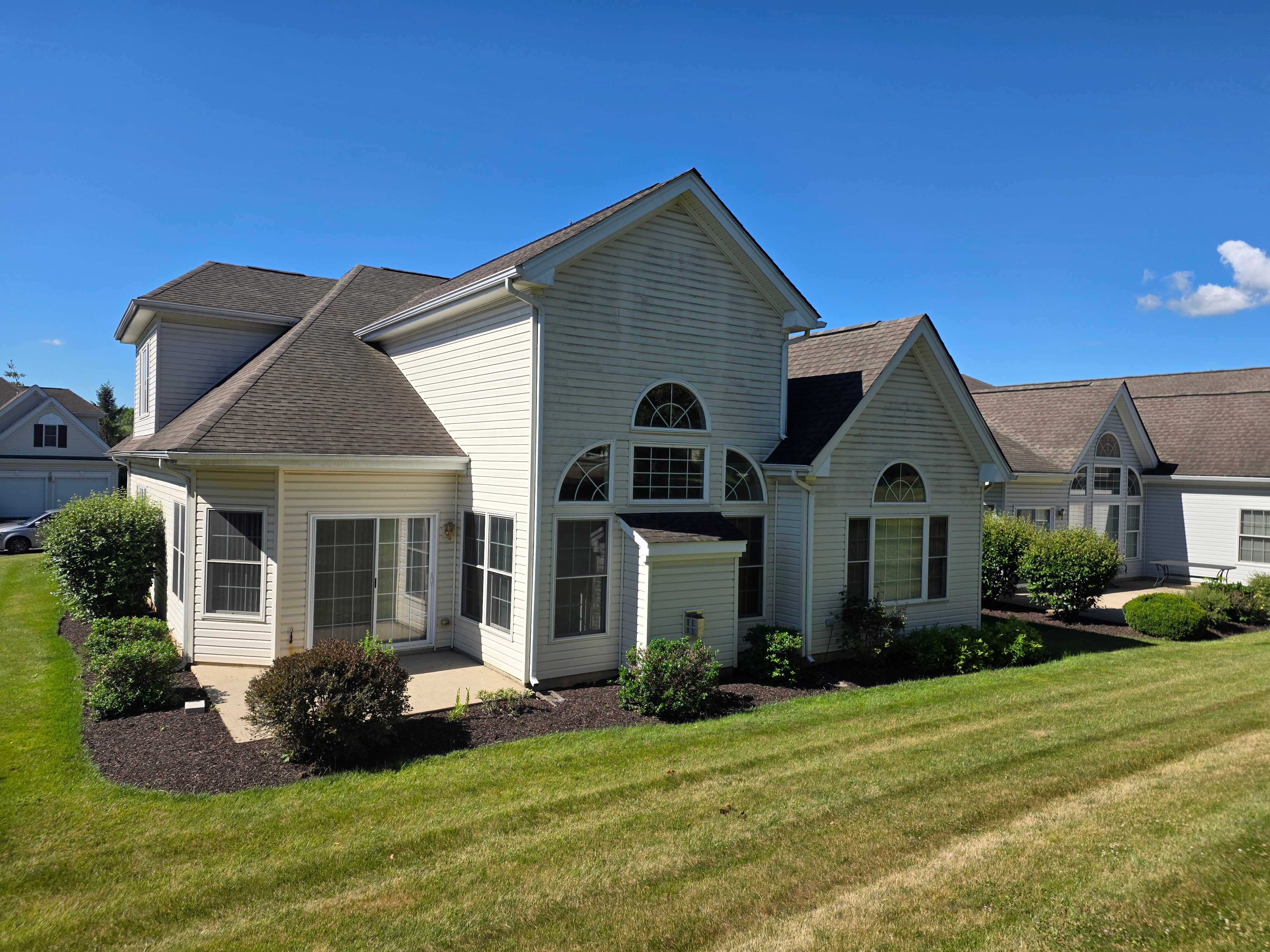 Rear exterior showing patio, circle-top windows, and mature landscaping