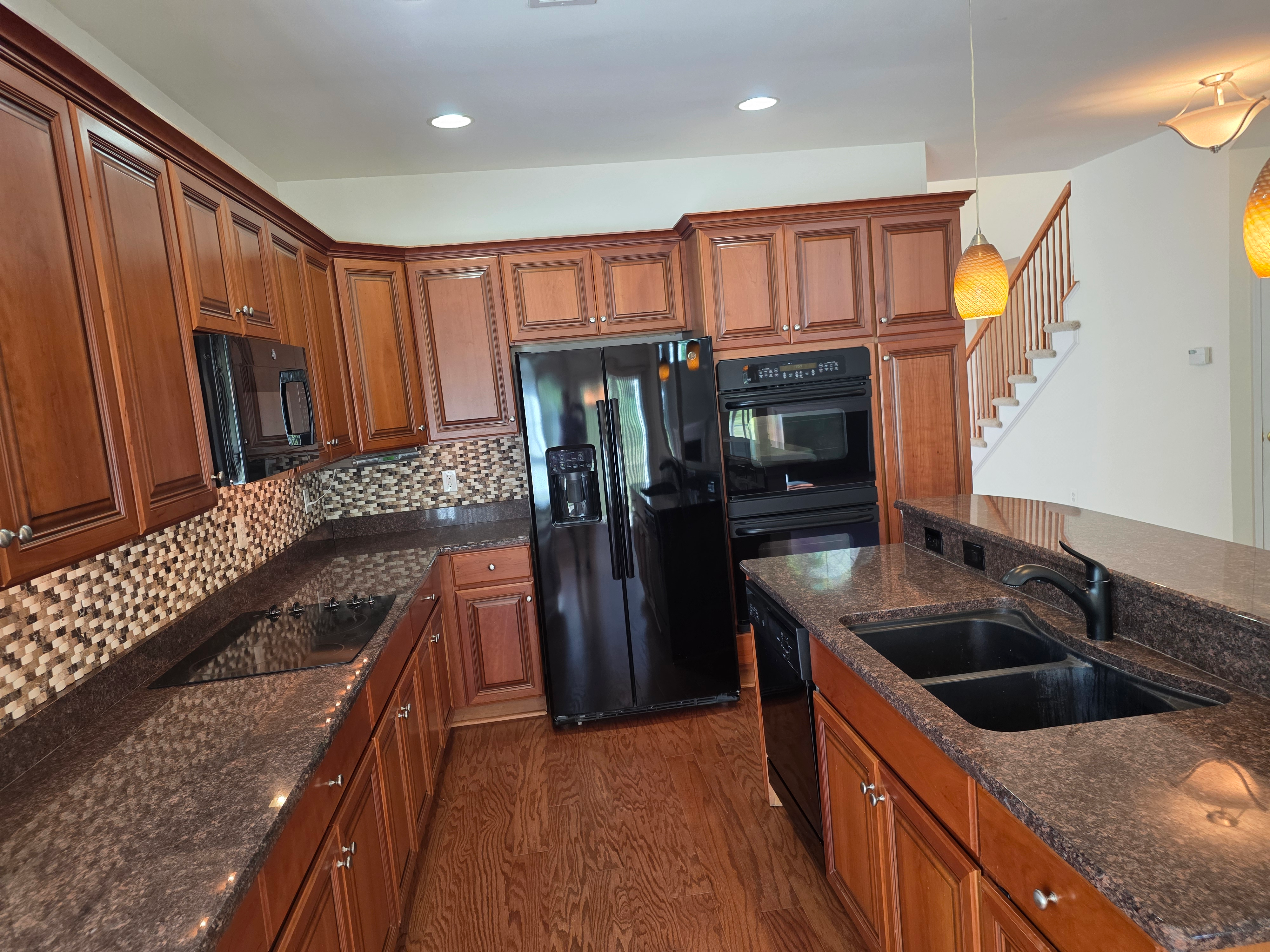 Kitchen with wood cabinetry, granite counters, and tile backsplash