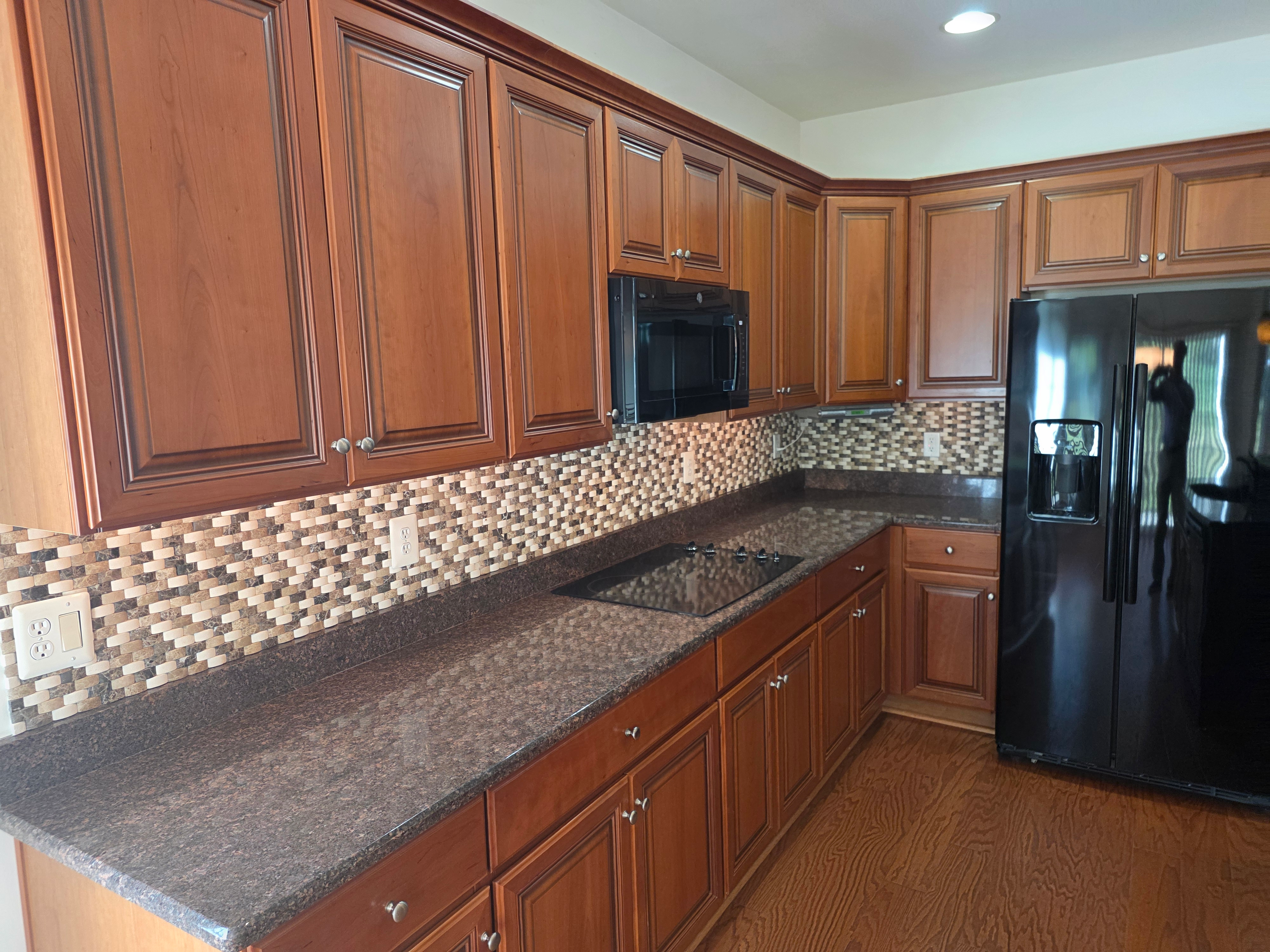 Kitchen cabinetry with built-in appliances and tile backsplash
