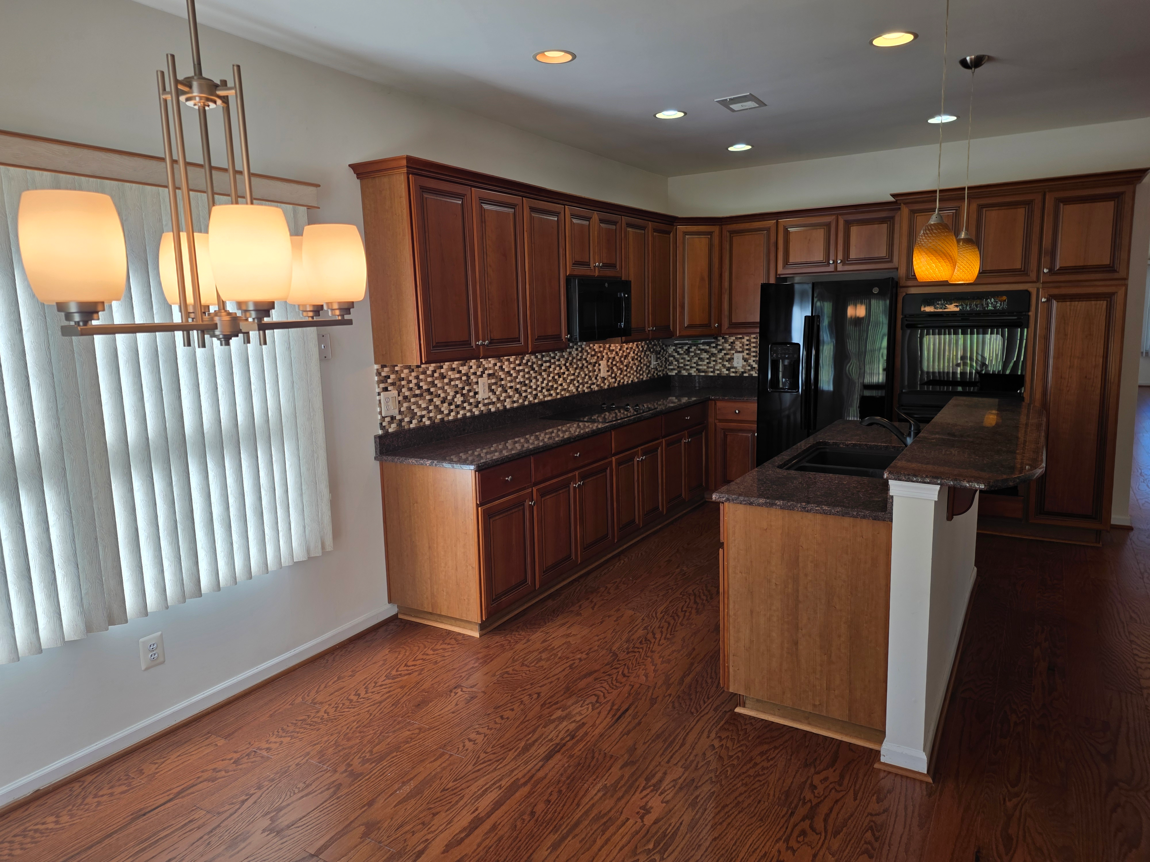 Kitchen with dark wood cabinetry, granite countertops, and hardwood floors