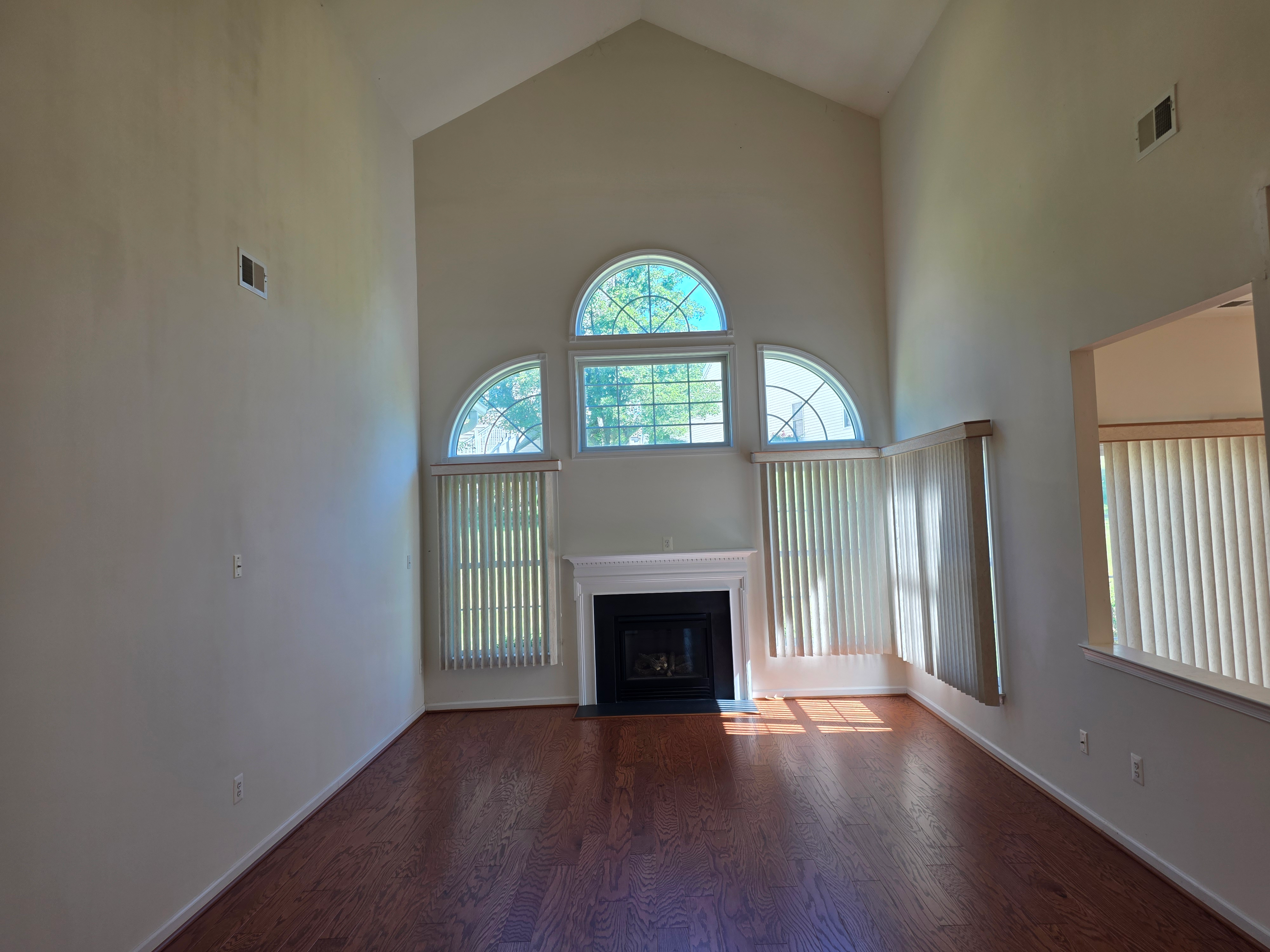 Living room with vaulted ceilings, hardwood floors, and gas fireplace