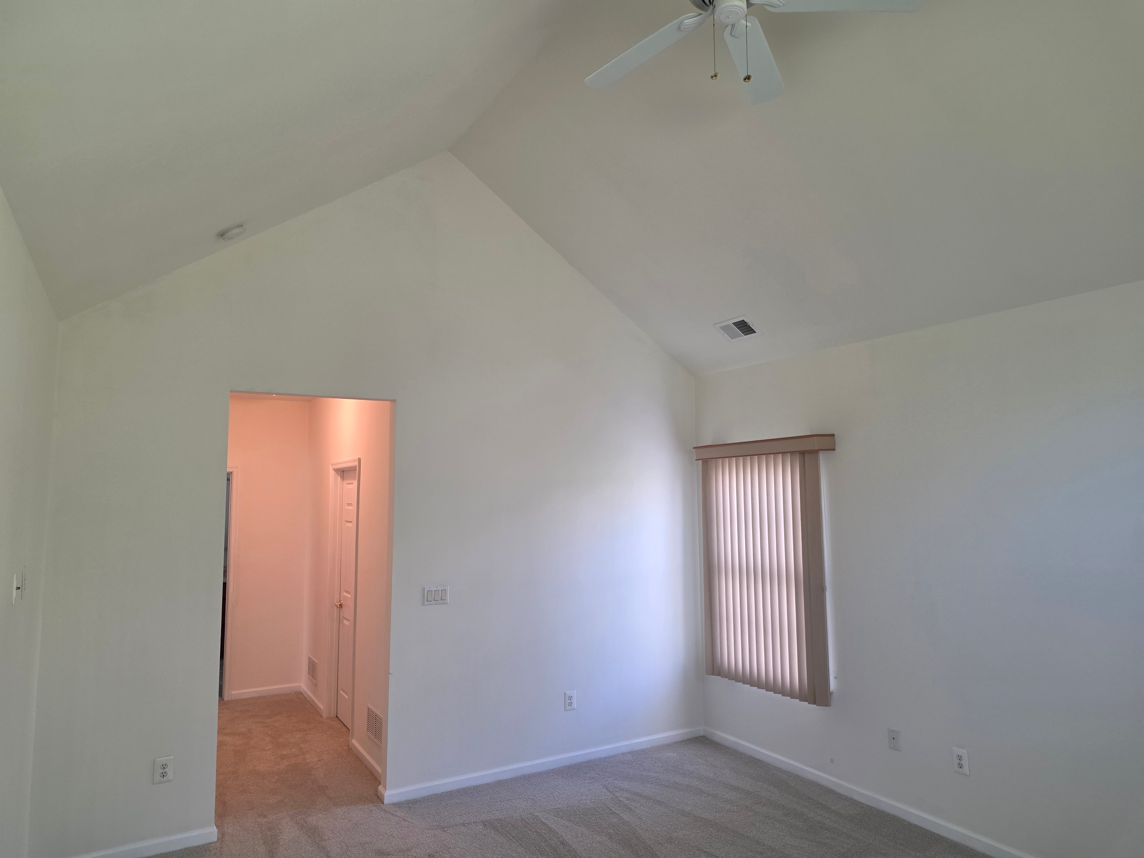 Vaulted living area with high ceilings and neutral walls