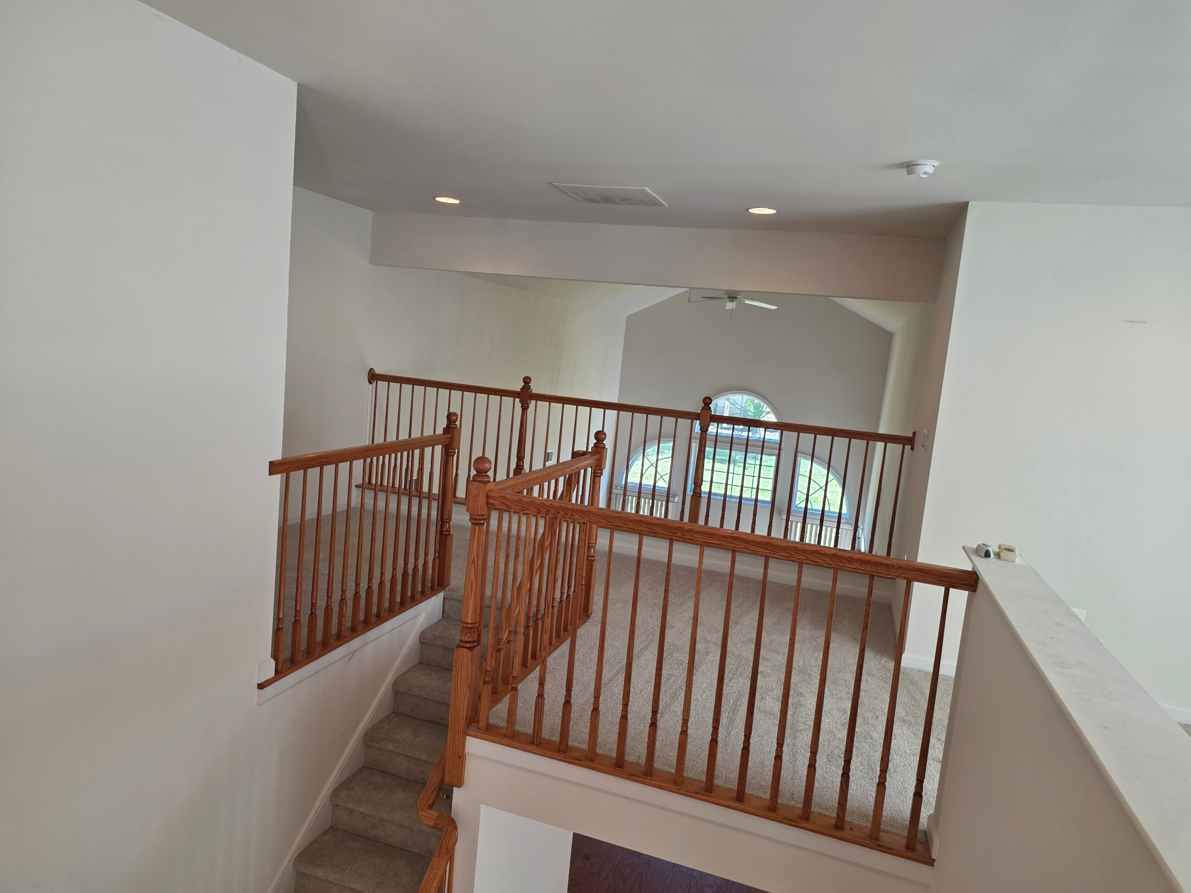 Carpeted loft overlooking main level with wood railings