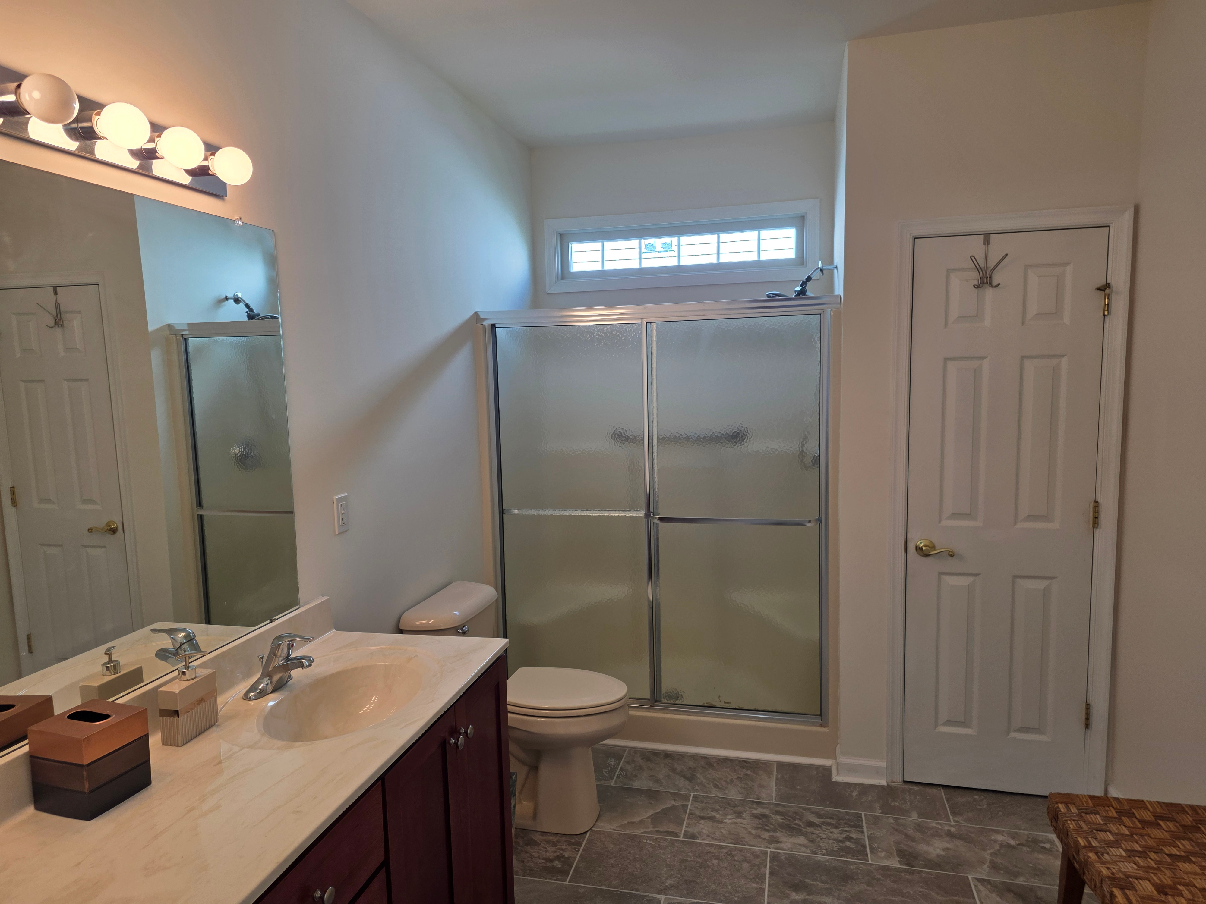 Full bathroom with stone-look tile floors and vanity