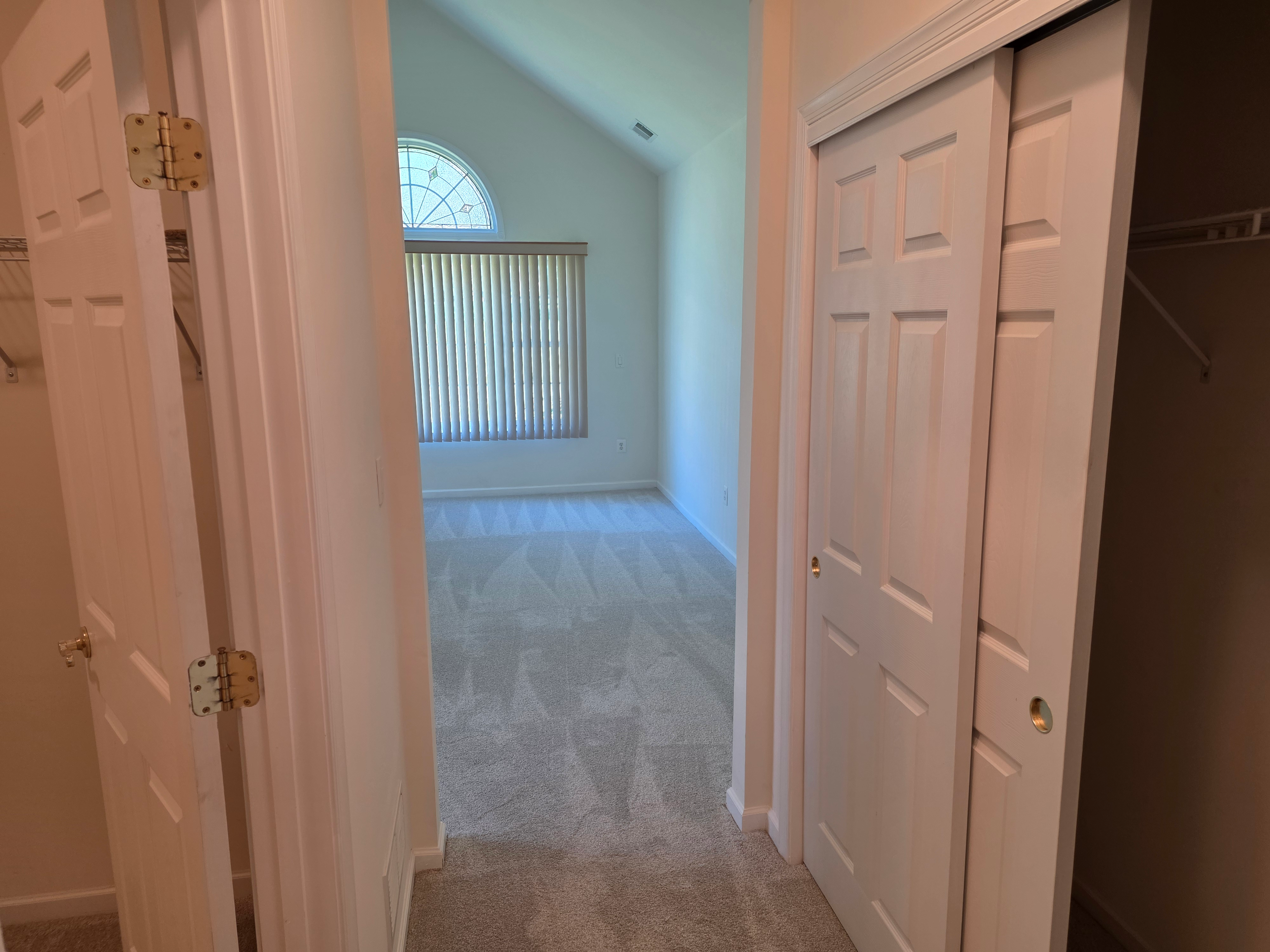 Bedroom entry showing closet doors and vaulted ceiling