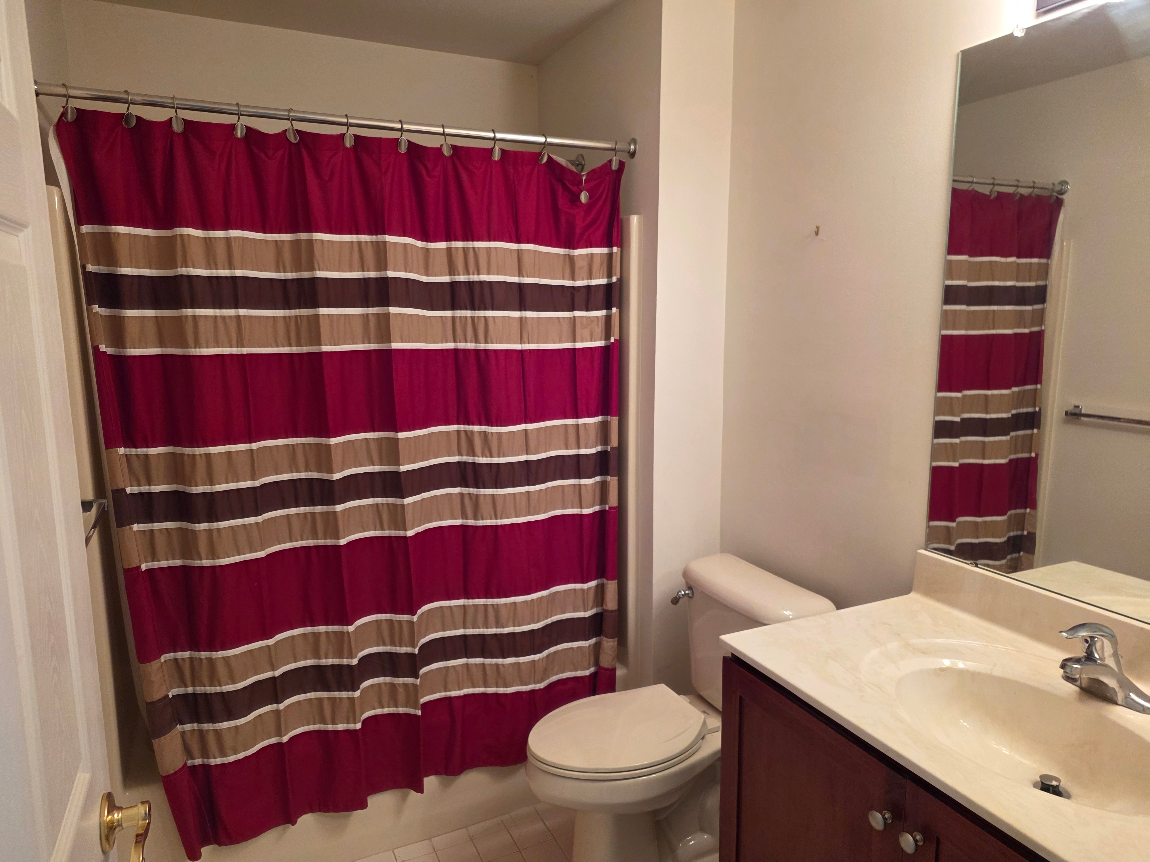 Full bathroom with cherry-toned vanity and shower
