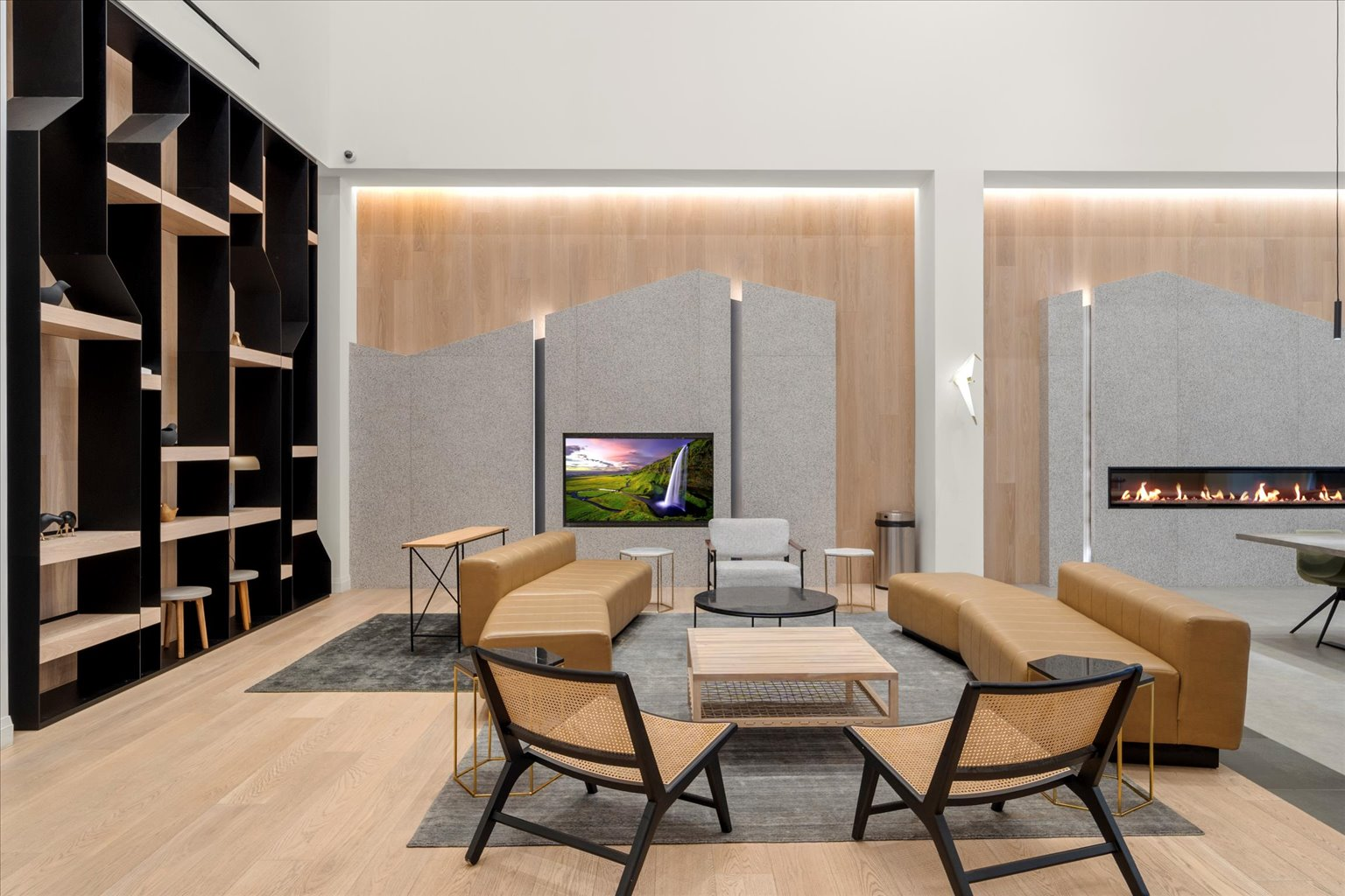 Social lounge with linear fireplace, stone wall, and leather seating