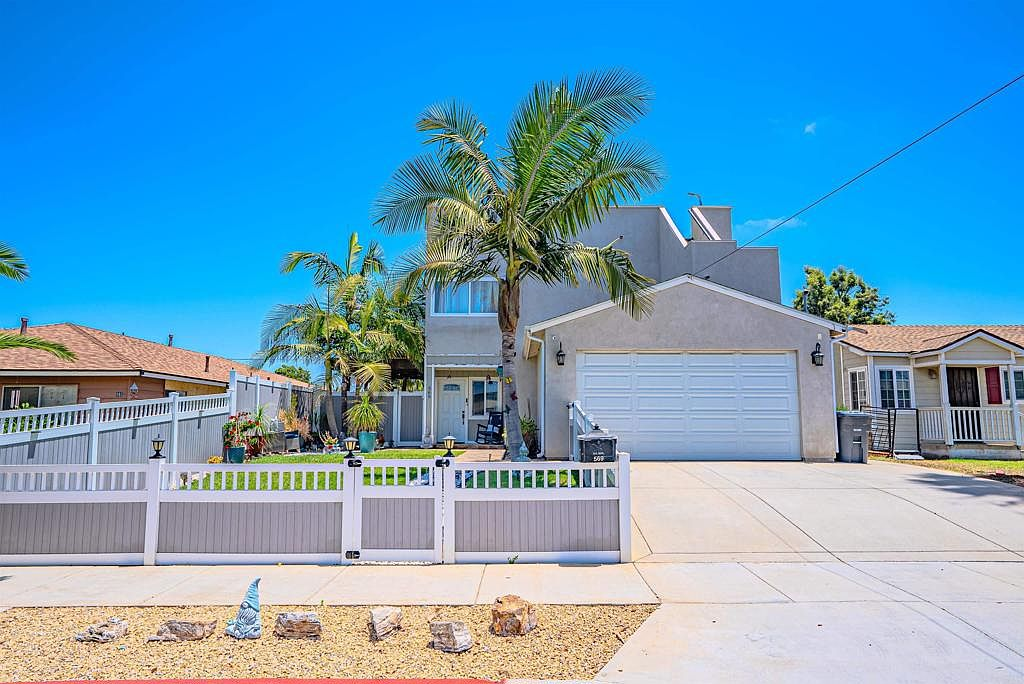 Two-story home with white vinyl privacy fencing and concrete driveway