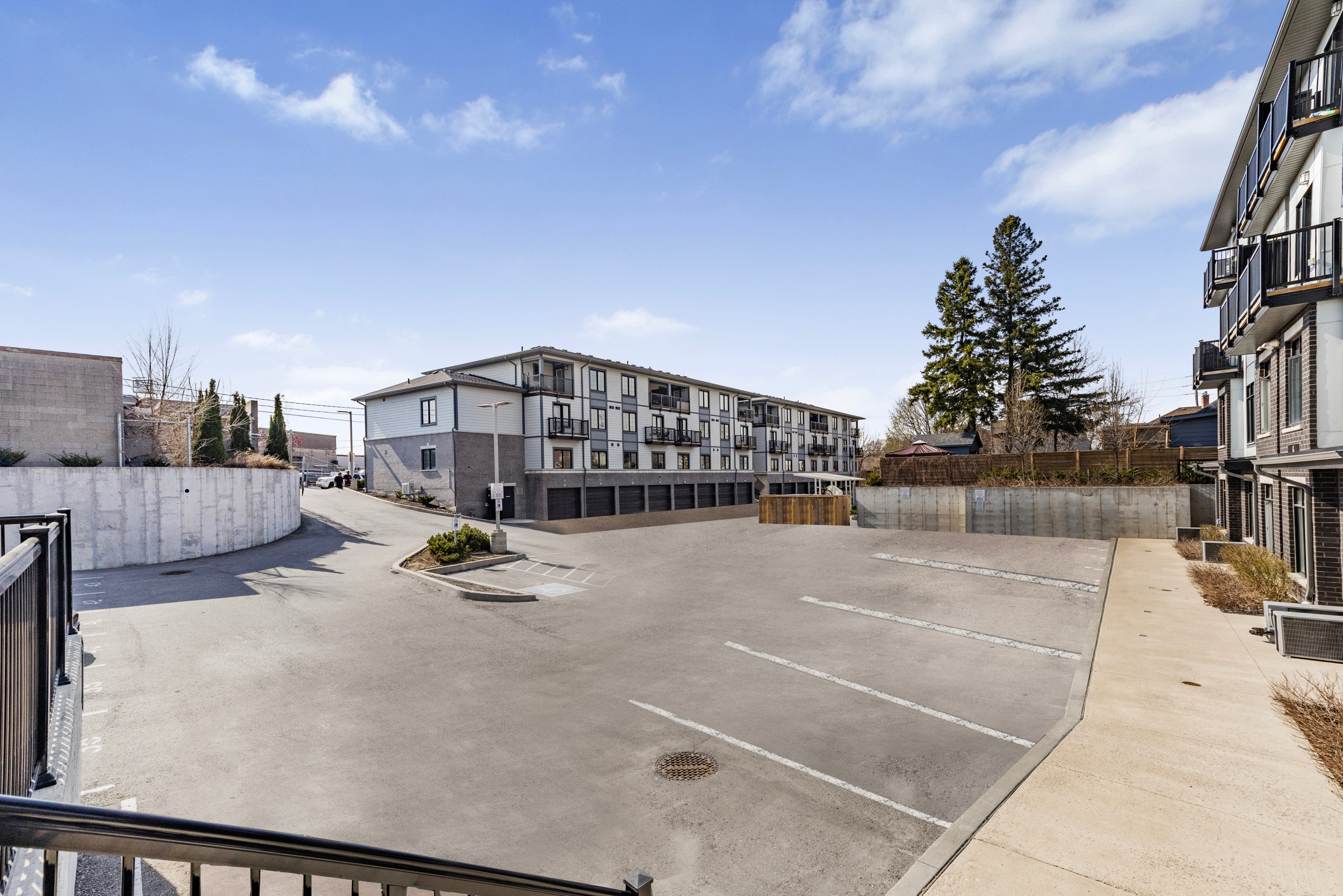 Wide-angle view of the townhouse complex parking lot and building exterior under a clear blue sky
