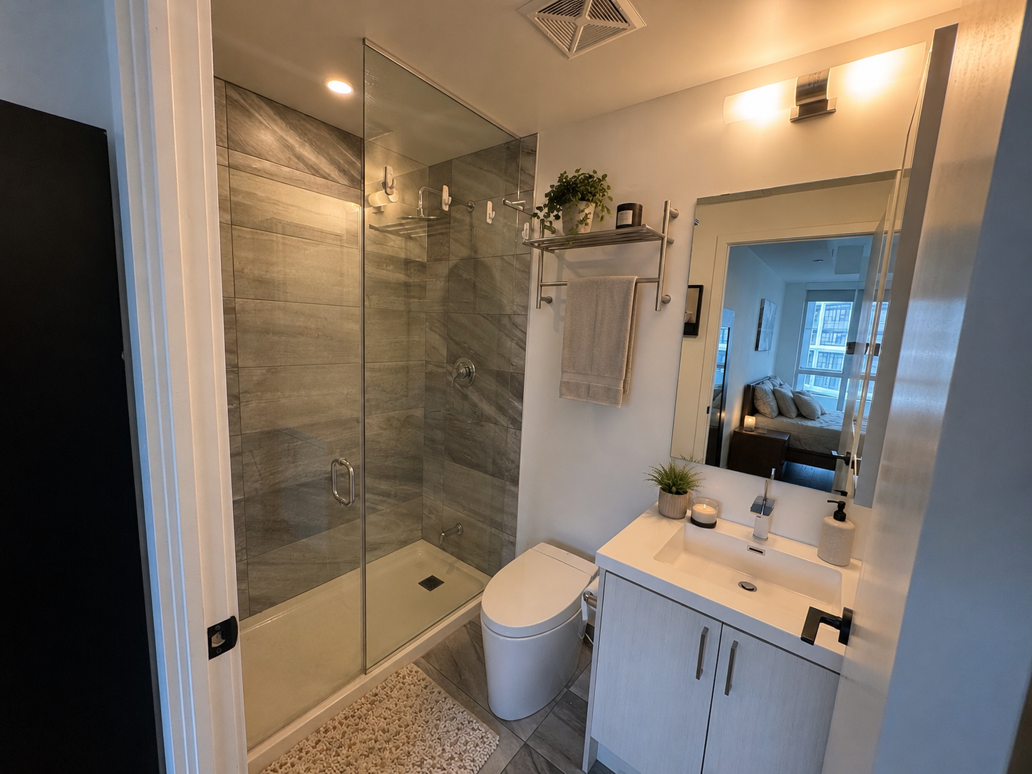 Main bathroom with grey tile shower surround and white vanity