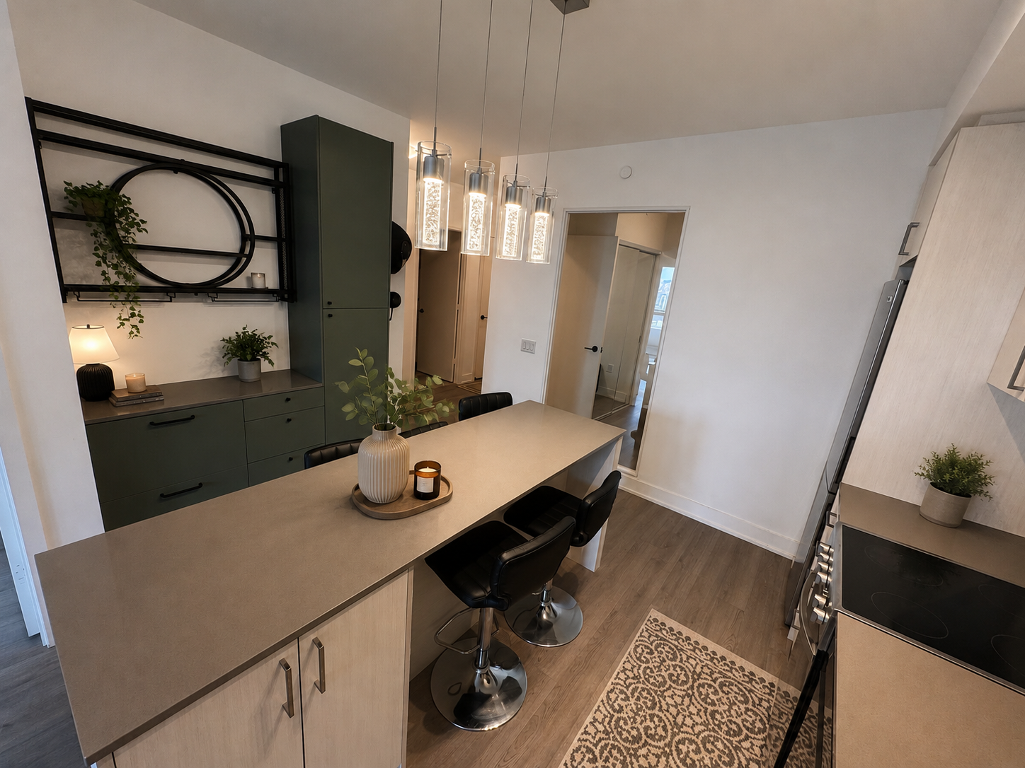 Kitchen with light wood-toned cabinets and dark olive-green accent cabinets, cylindrical pendant lights, galley-style layout