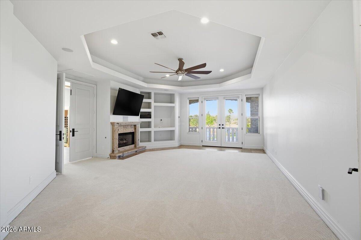 Living room with stone fireplace, built-in shelving, and French doors