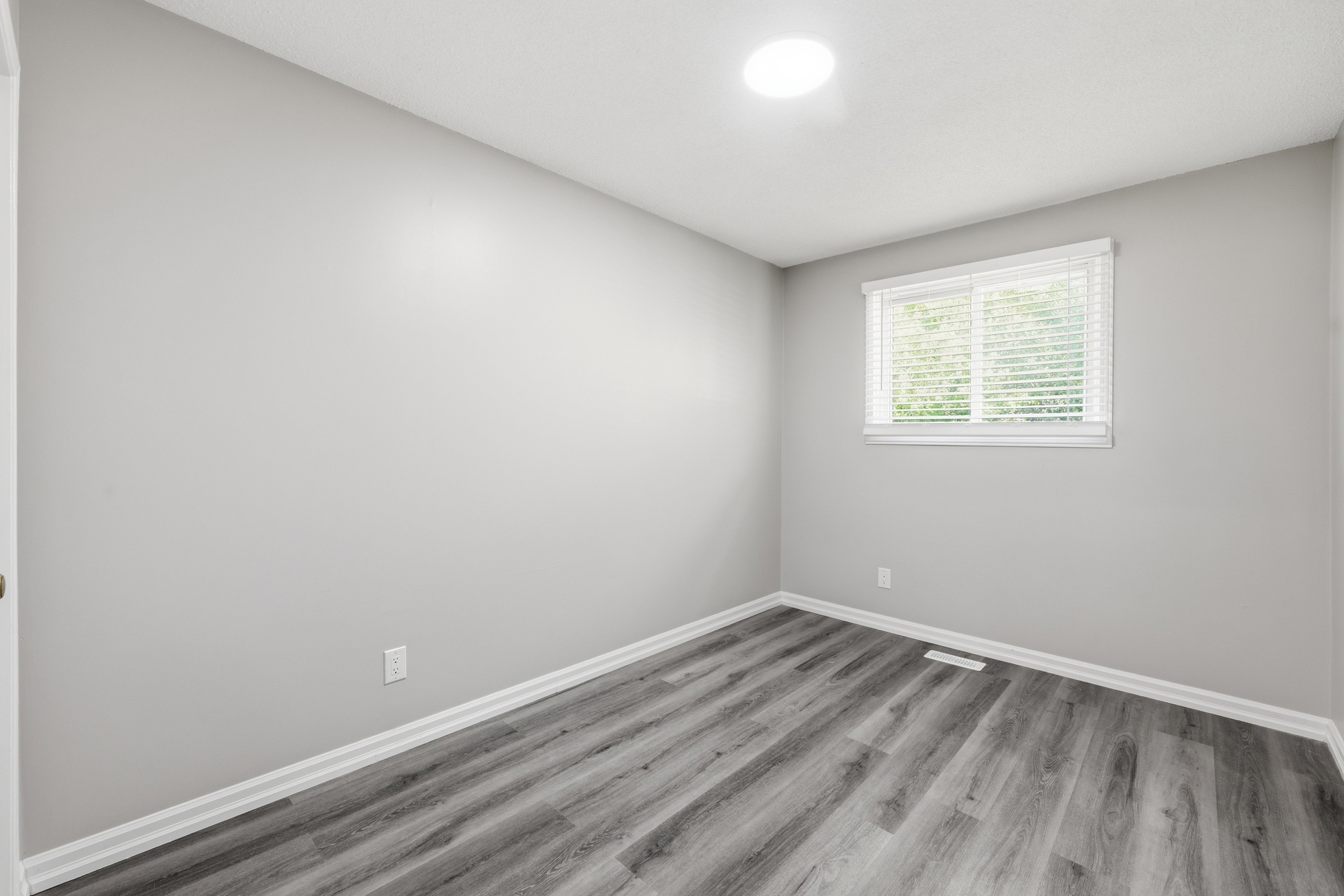 Vacant bedroom with new laminate flooring and natural light