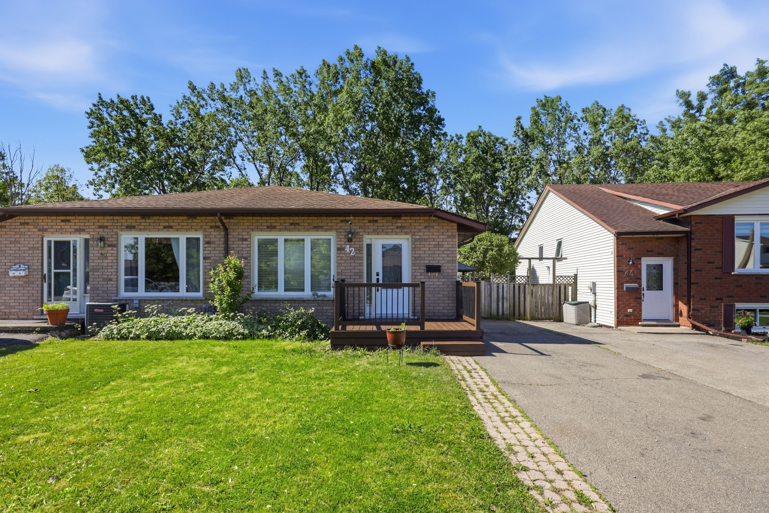 Front exterior of the semi-detached backsplit home with brick facade and front deck