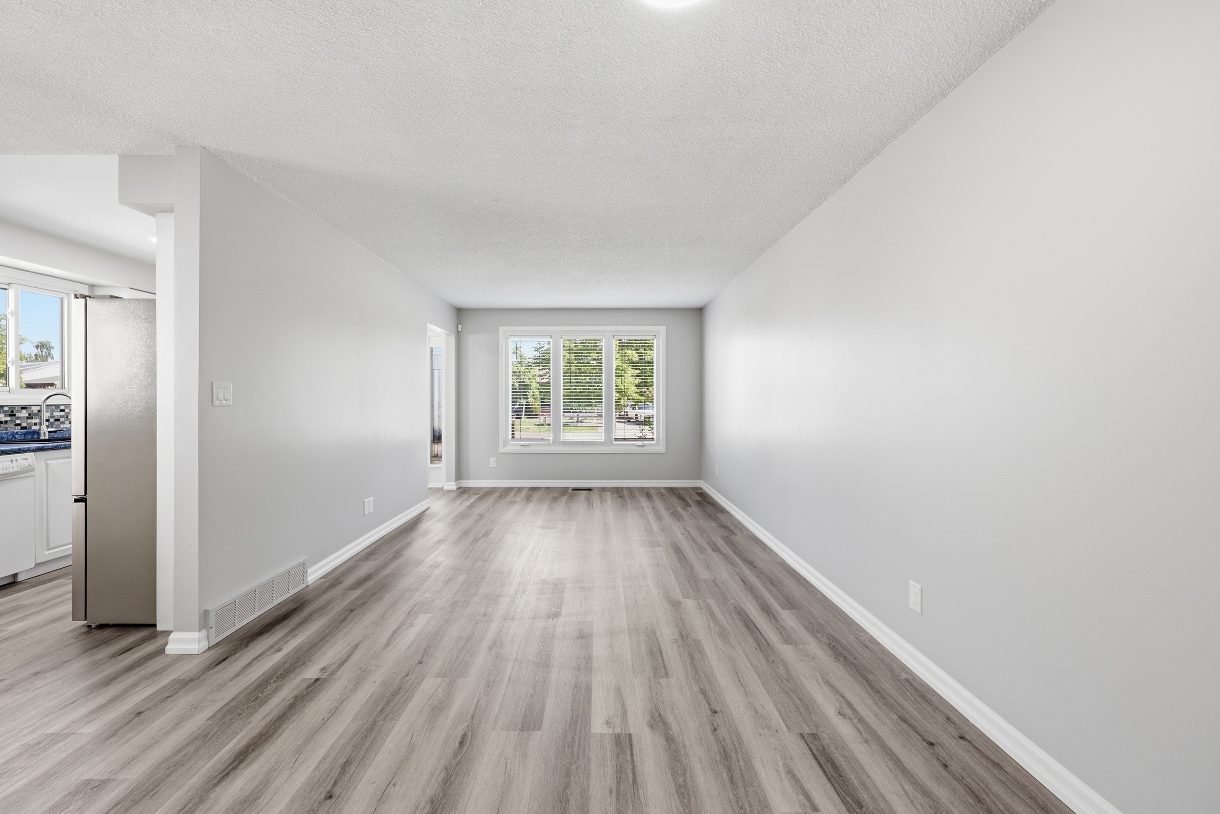 Open-concept living and dining area with new laminate flooring and natural light from large picture window