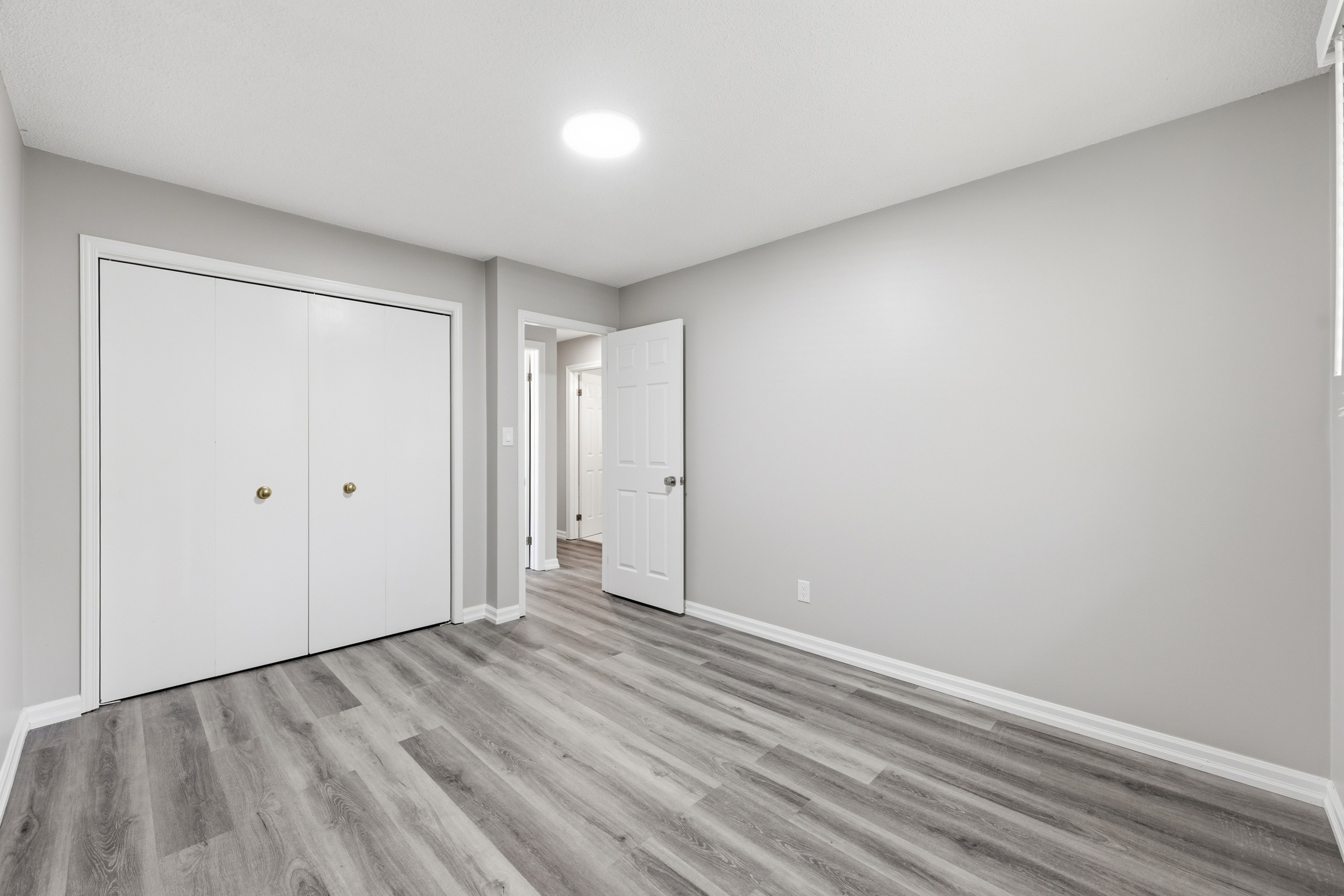 Wide-angle vacant bedroom with grey laminate
