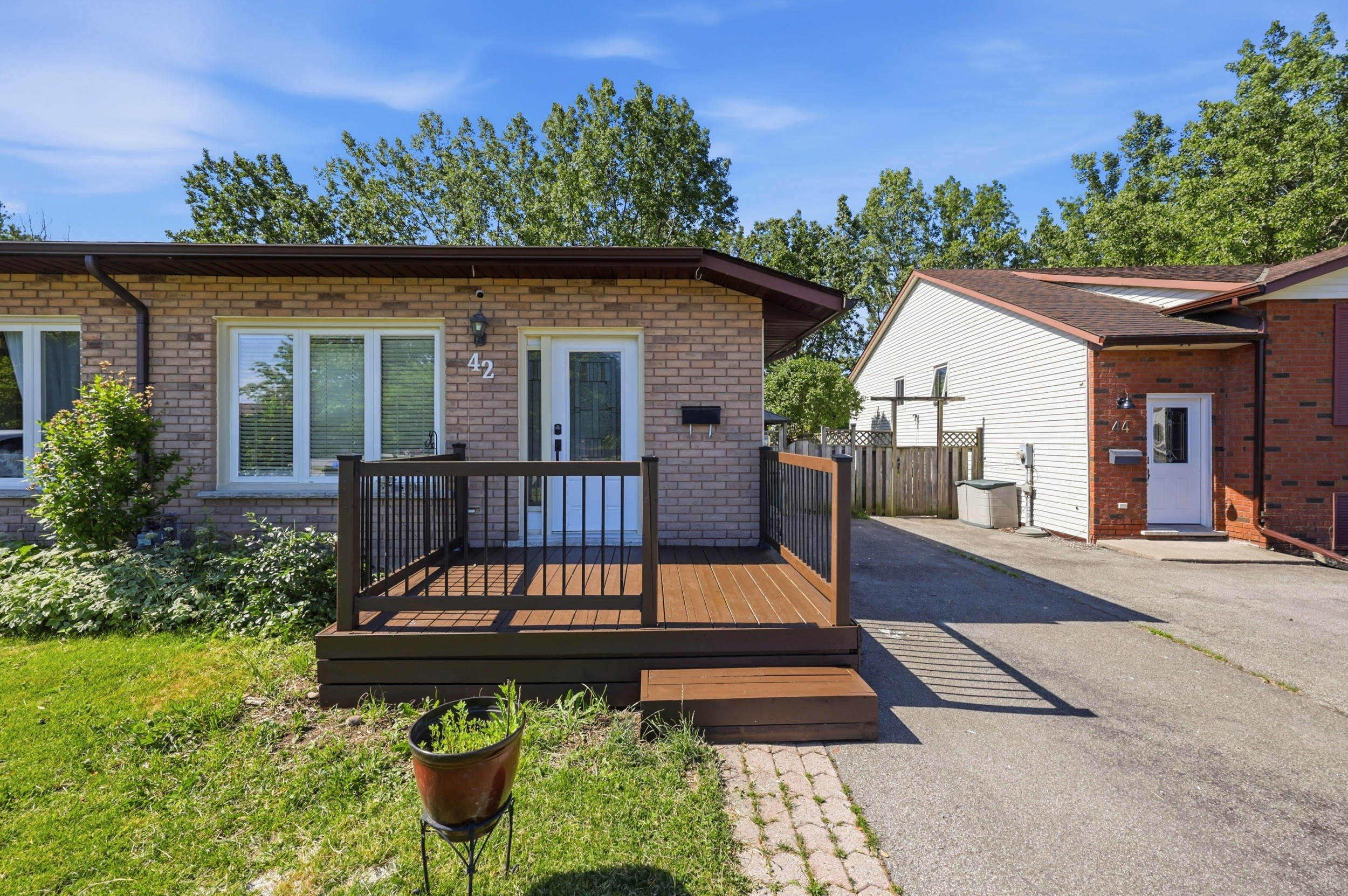 Exterior front view of this Welland backsplit home with brick facade and elevated wood deck