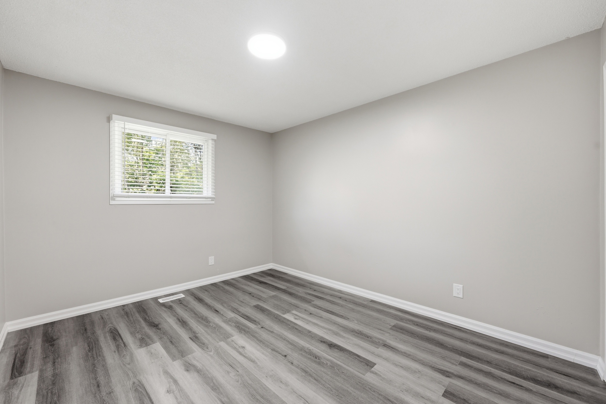 Vacant bedroom with grey flooring and window blinds