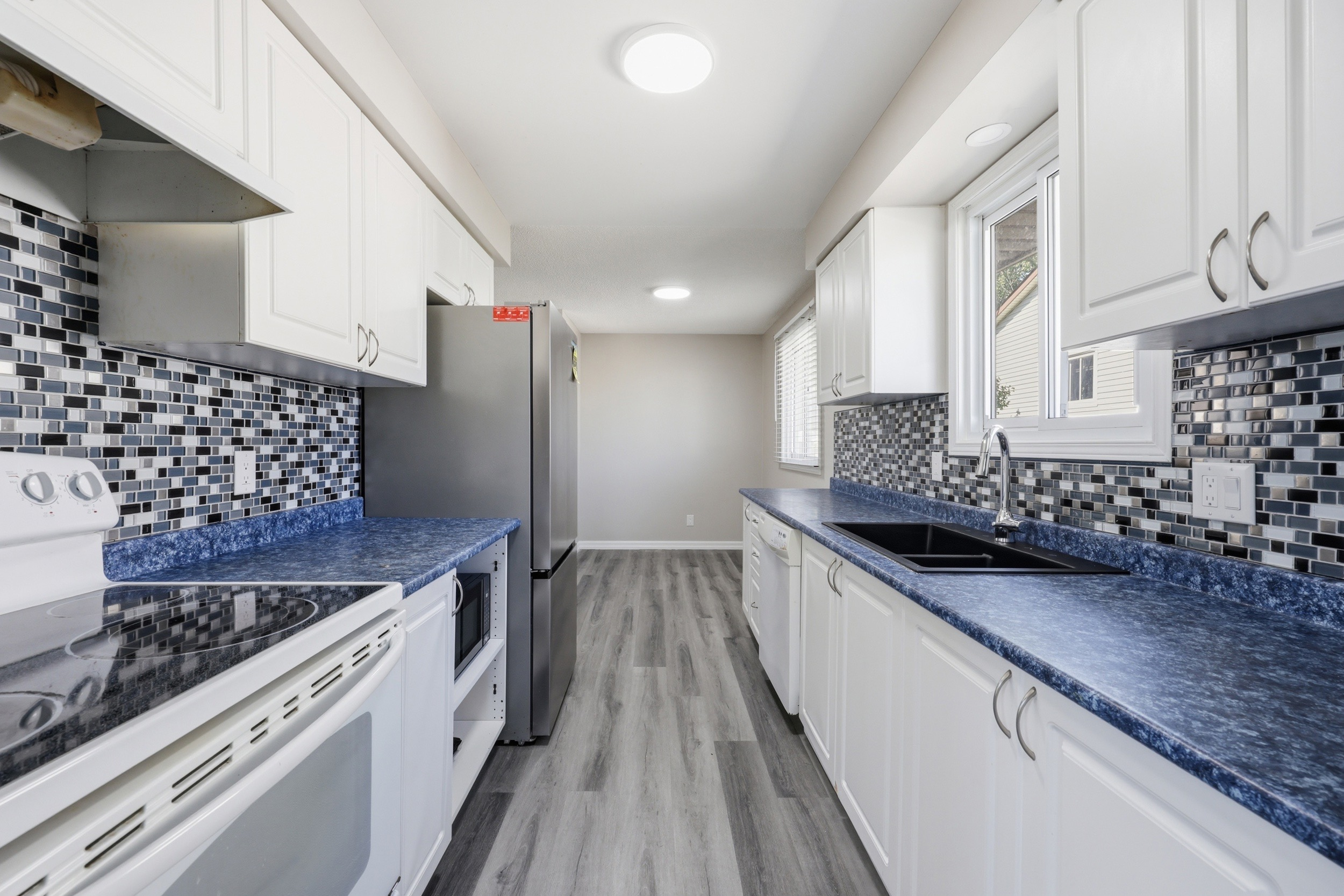 Galley kitchen with white shaker cabinets and blue countertops