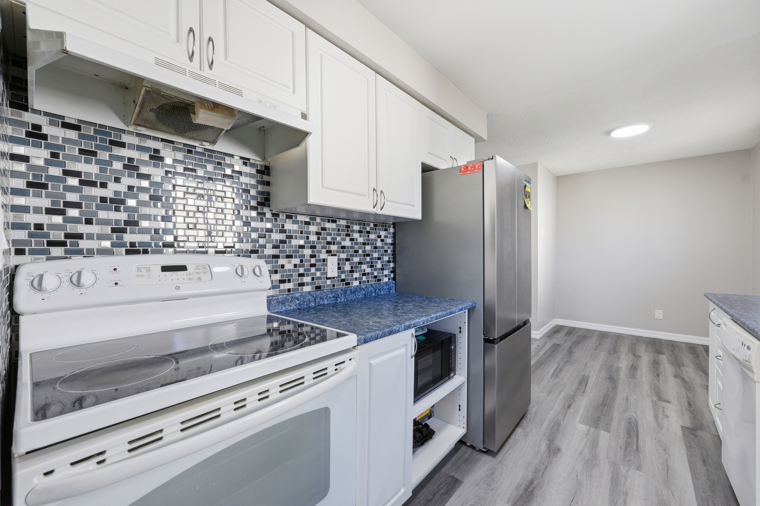 Kitchen with white shaker cabinets and glass tile backsplash