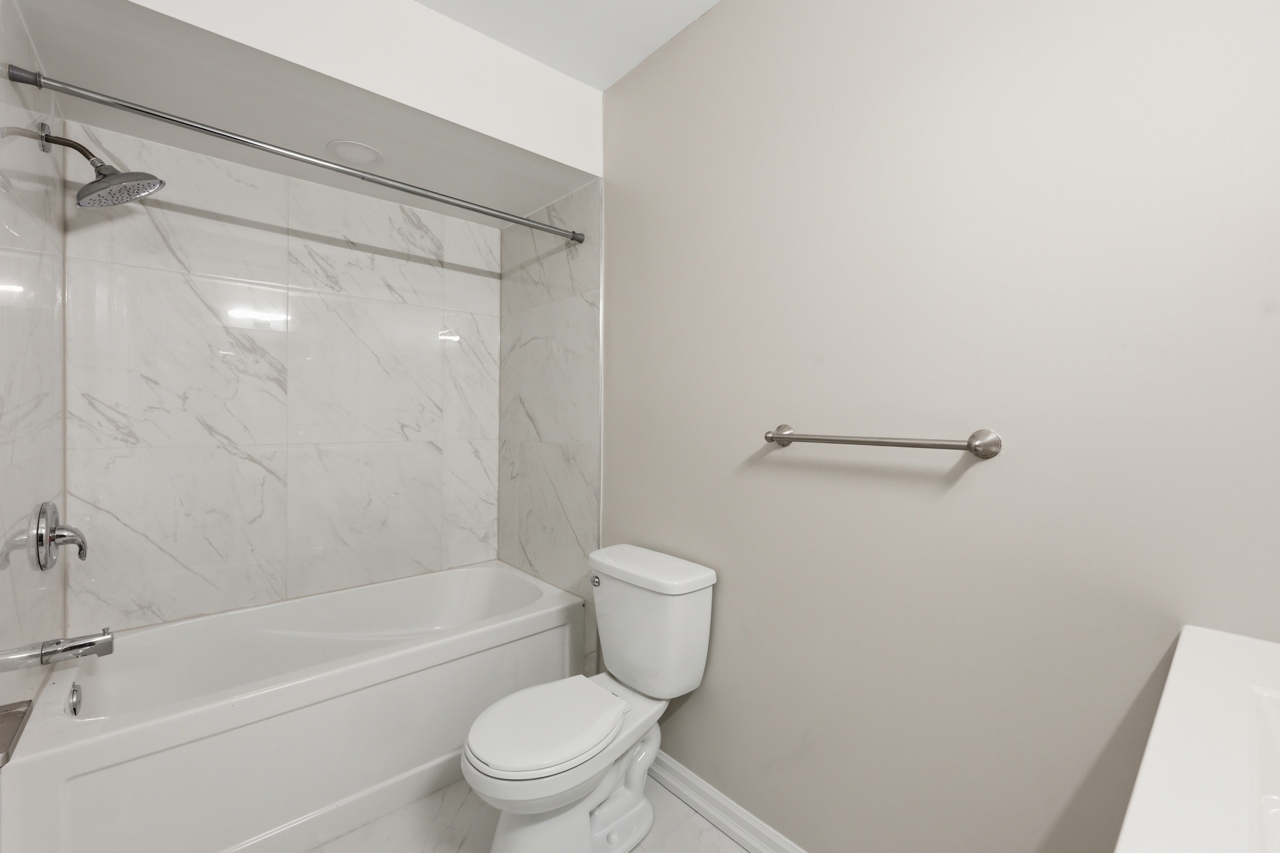 Updated main bathroom with marble-look tile surround and polished chrome fixtures