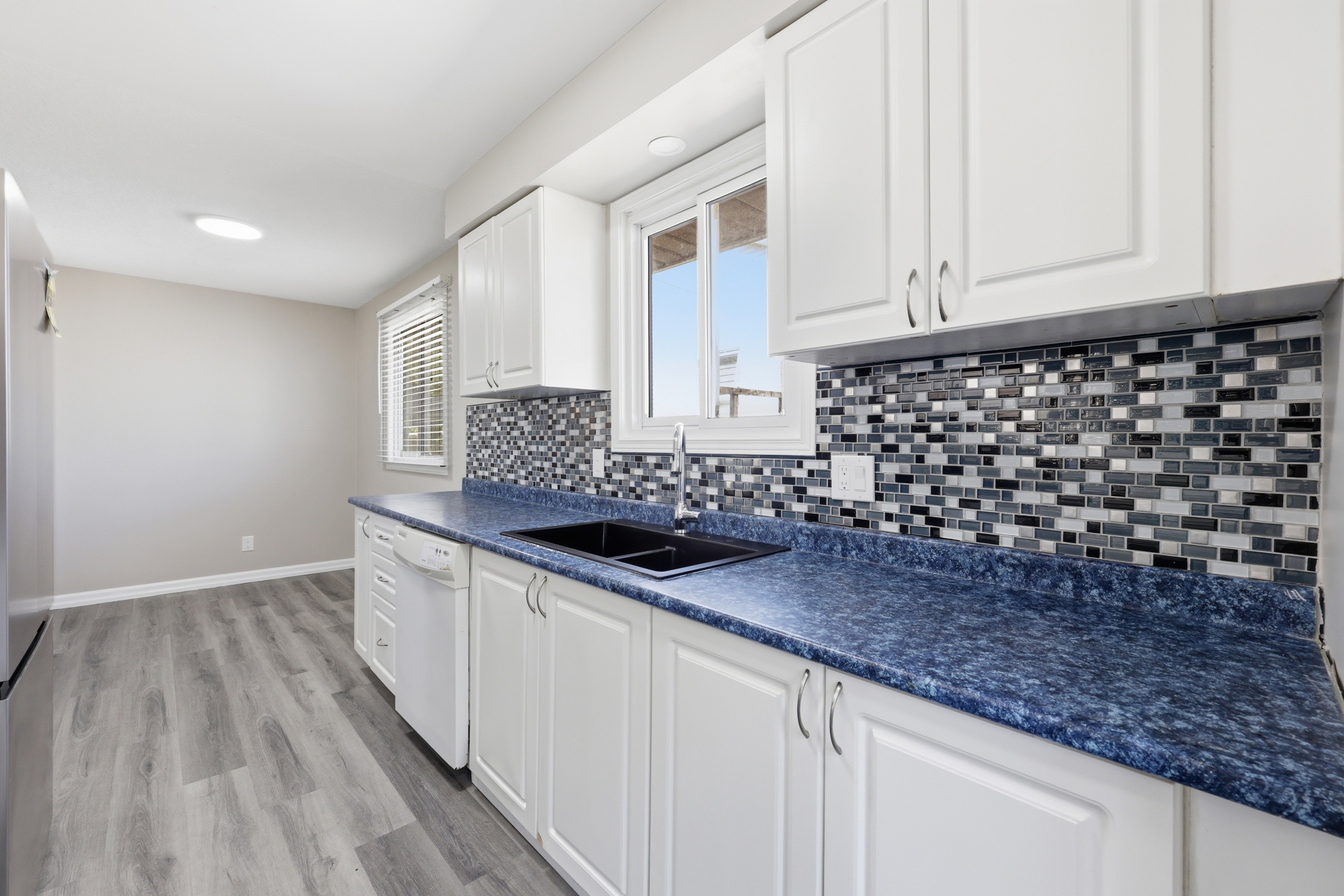 Kitchen with white cabinetry, black sink, and blue laminate counters