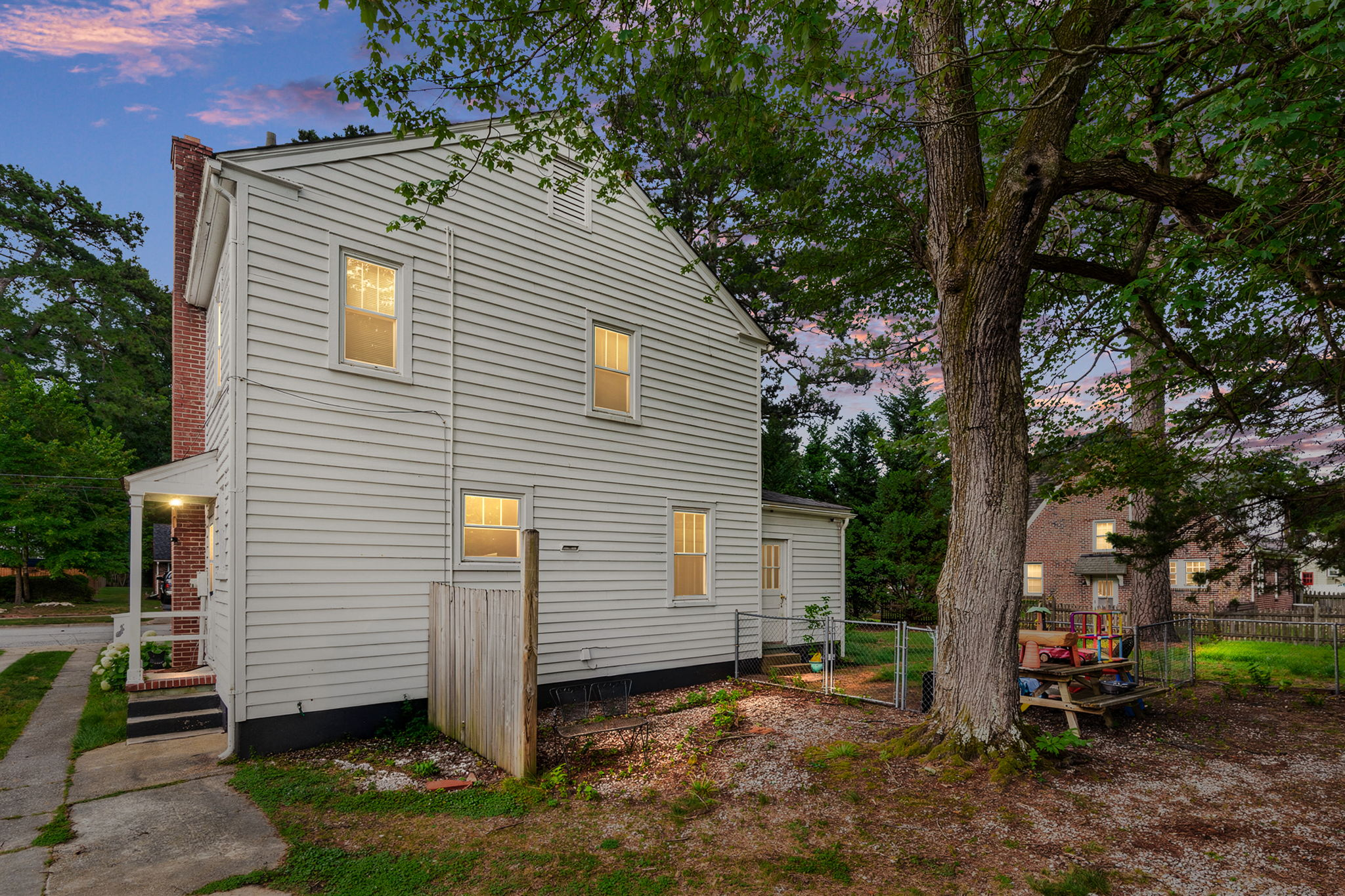 Side profile of the home with brick chimney at twilight