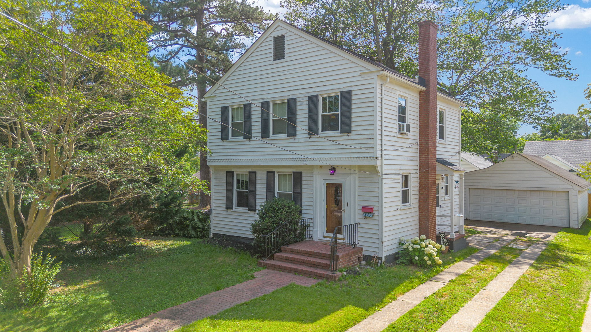 Two-story colonial facade with white siding and black shutters