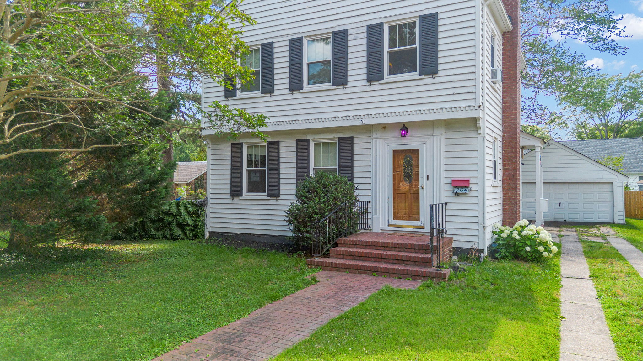 Front facade with brick walkway and detached garage visible