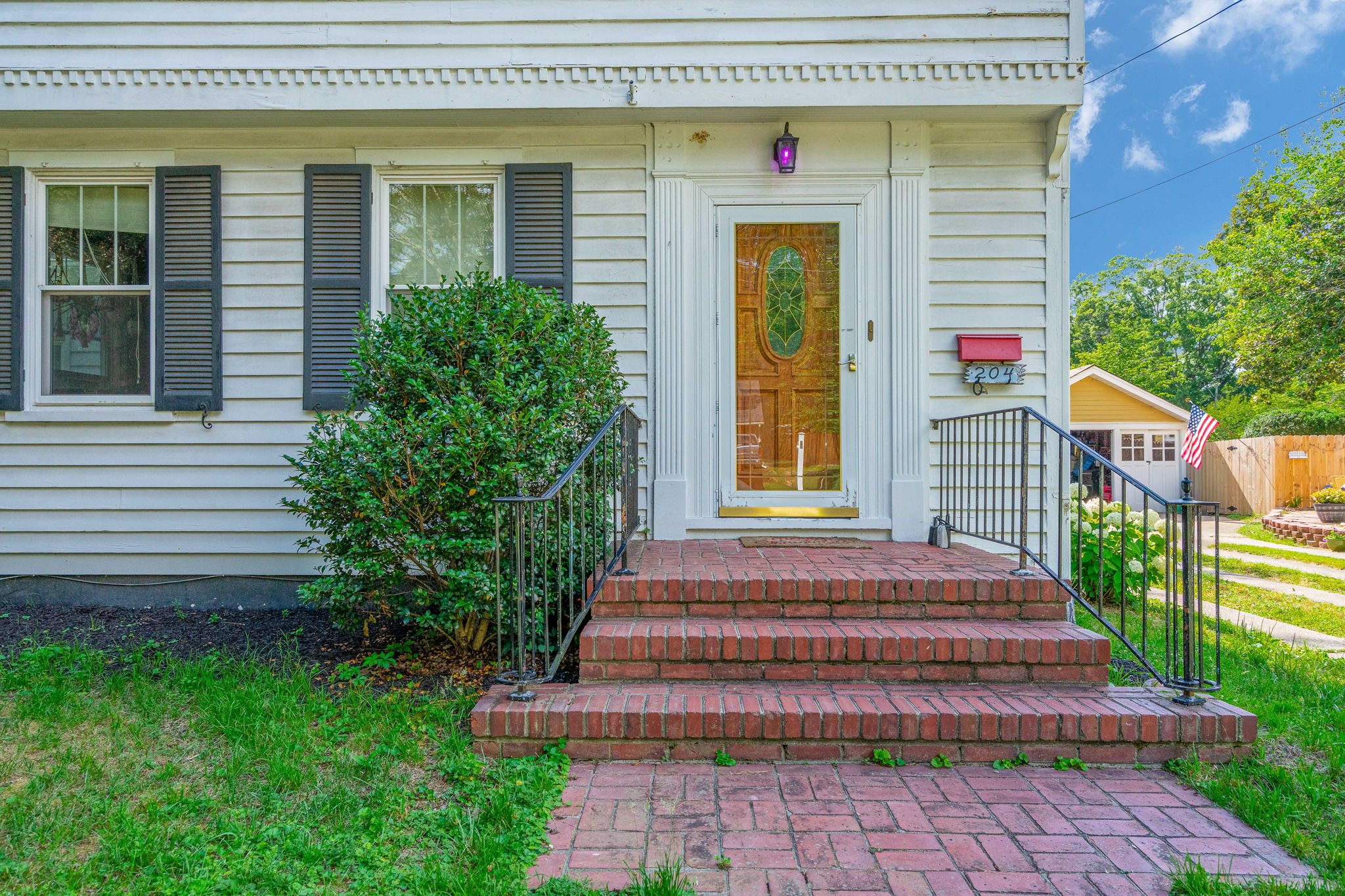 Front entrance with red brick steps and white siding