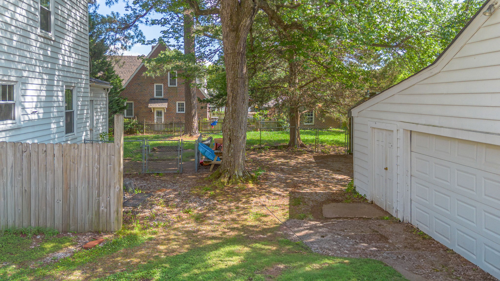 Backyard view showing detached garage and wooden fence