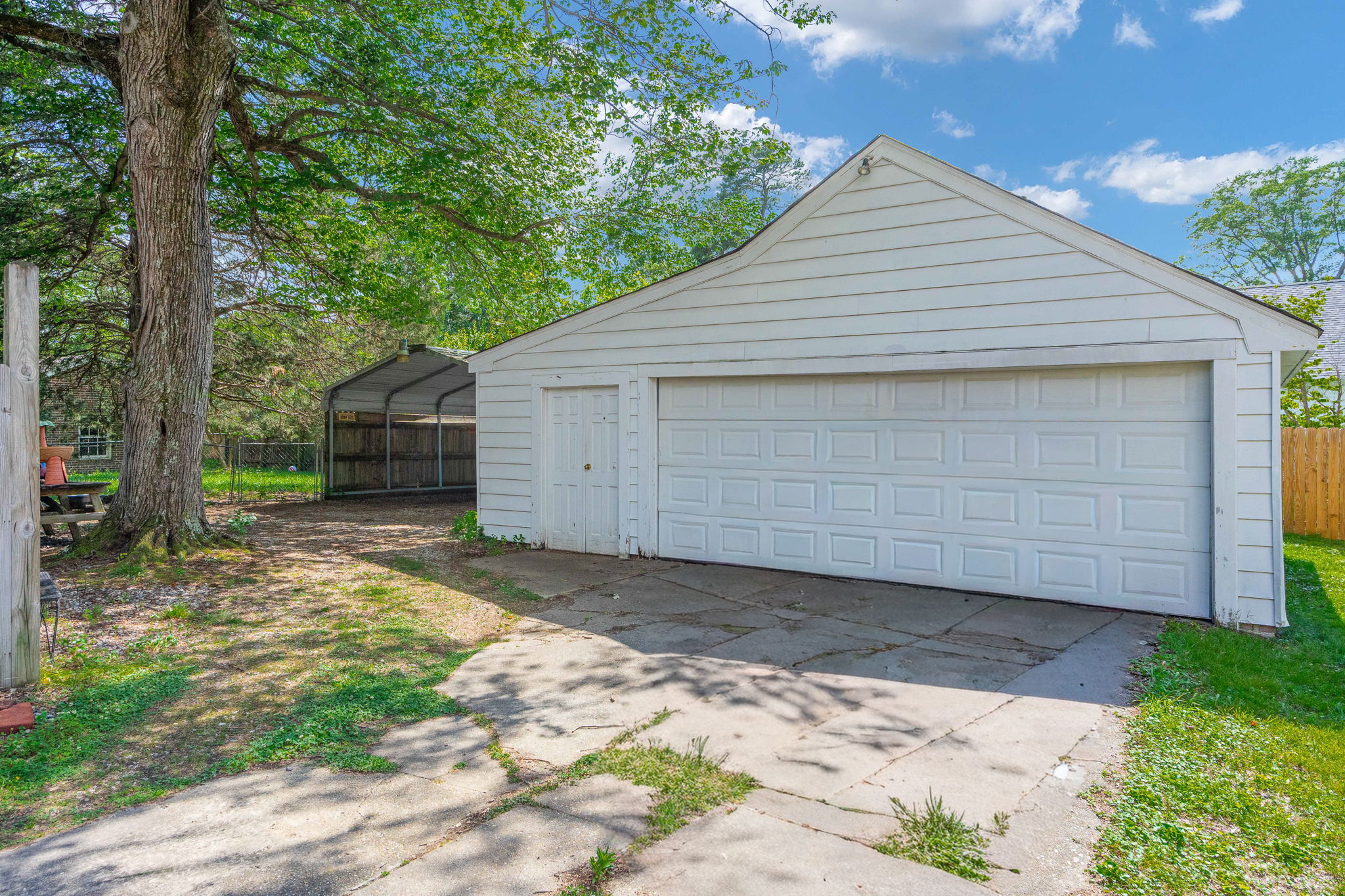 Detached white garage with siding and concrete driveway