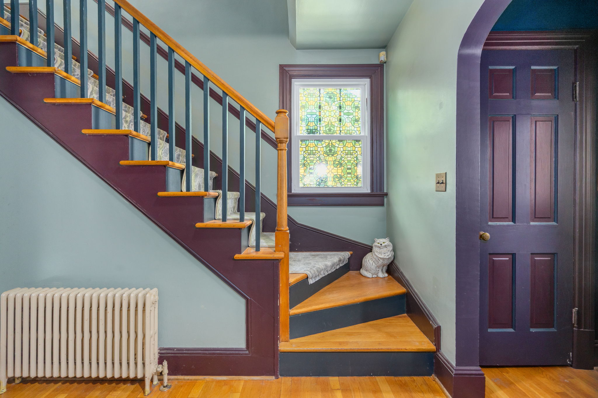 Home foyer with hardwood staircase and stained glass window