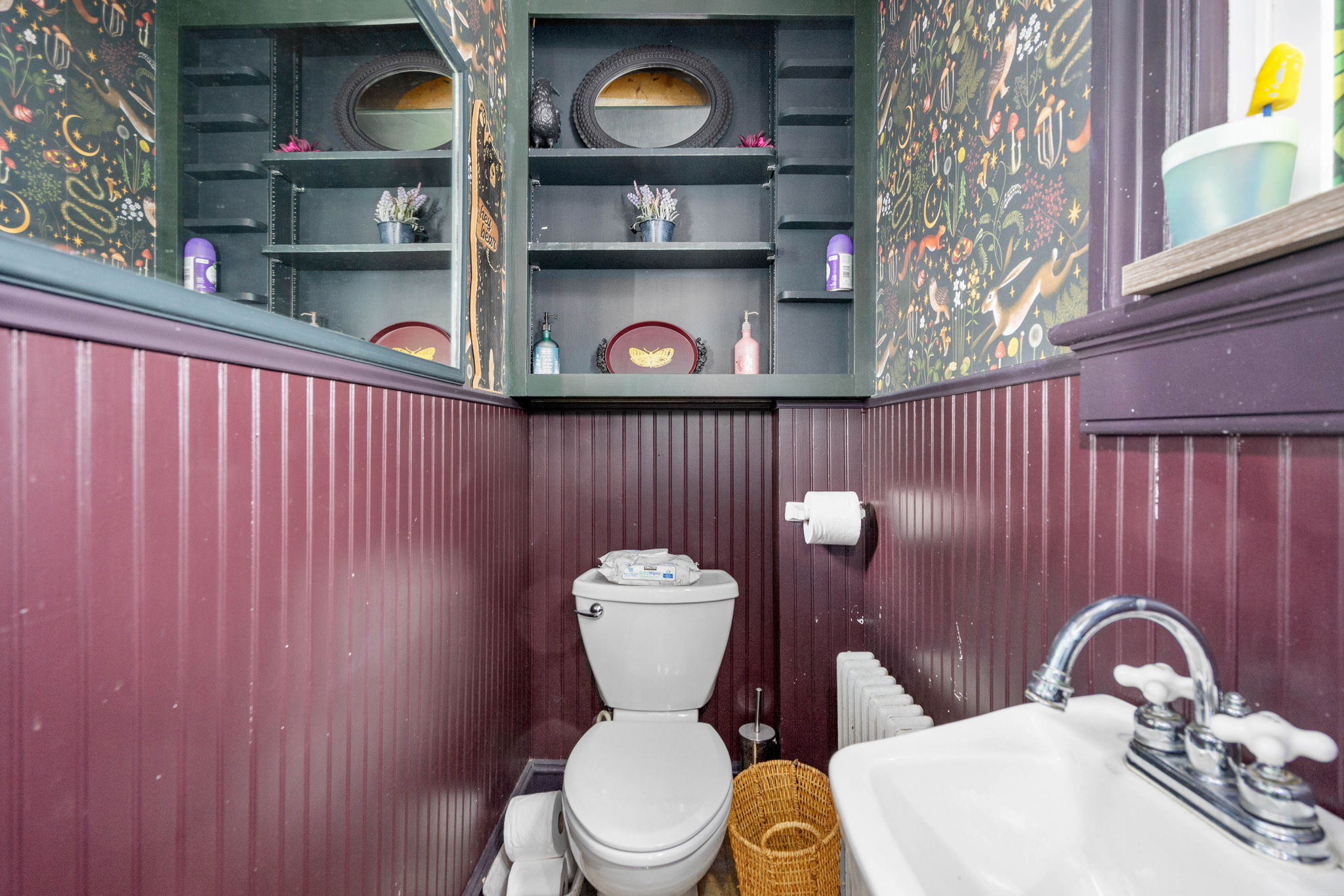 Bathroom with maroon beadboard wainscoting and botanical wallpaper
