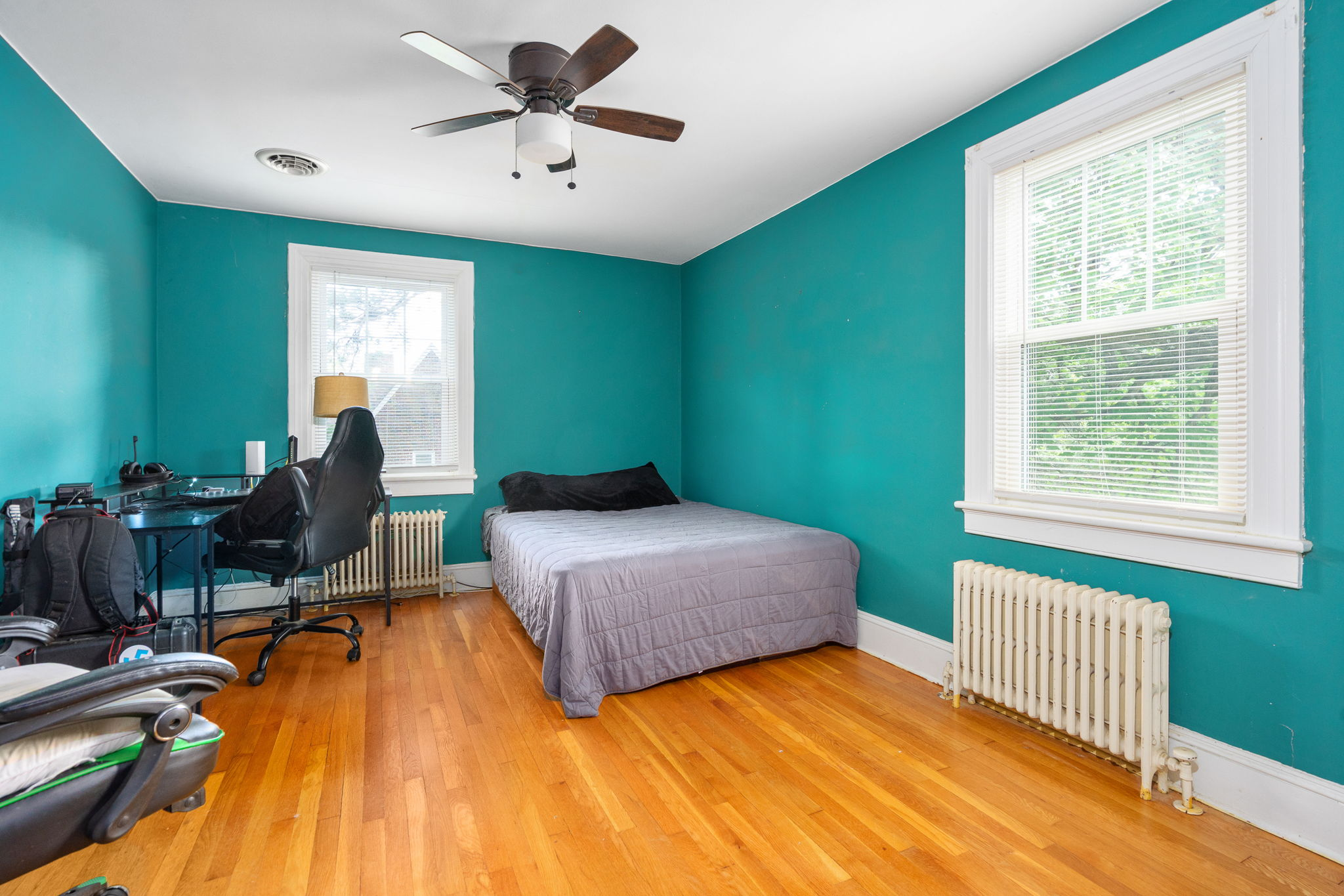 Bedroom with teal painted walls and hardwood flooring